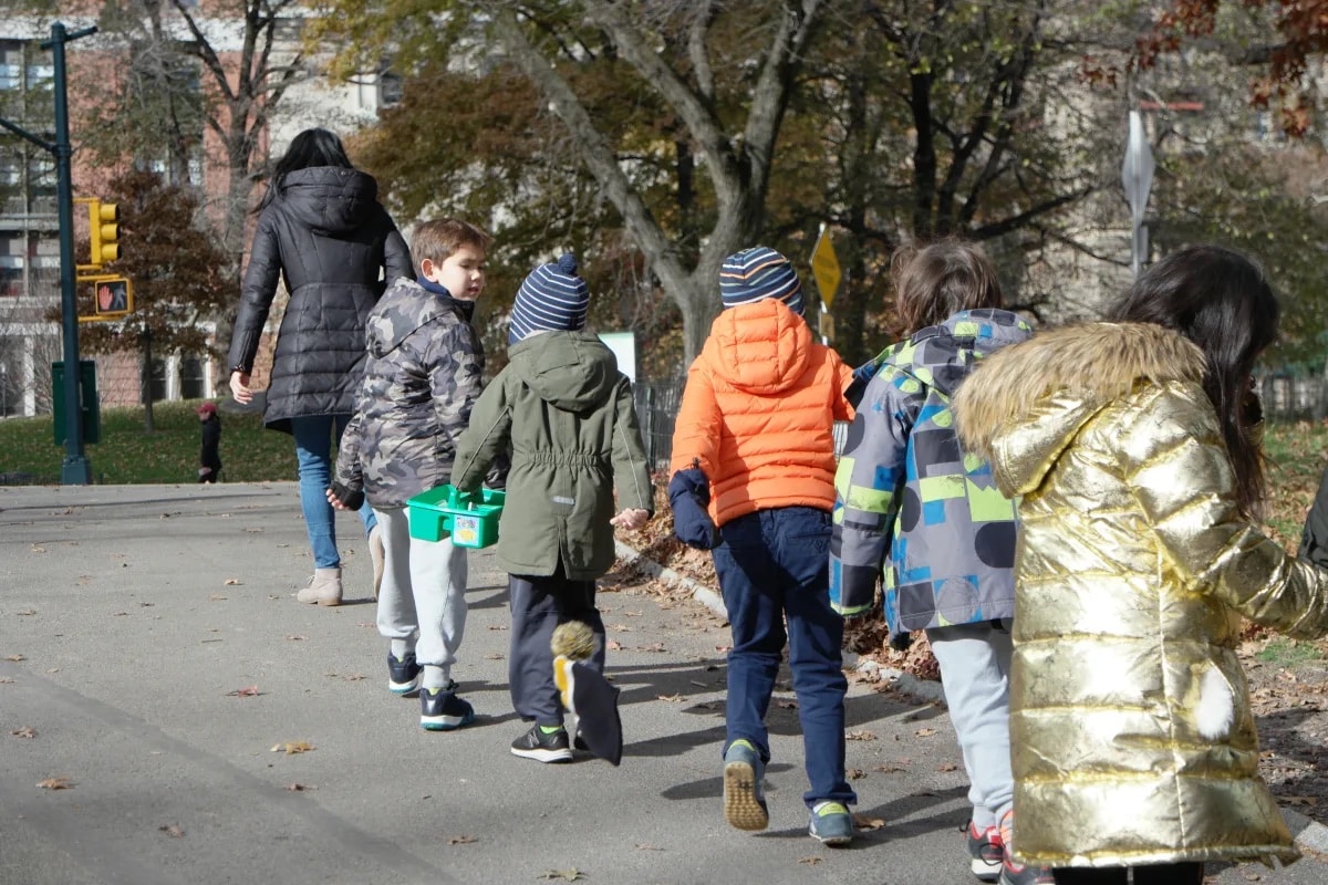 5 lower school students follow their teacher up a path in Central Park