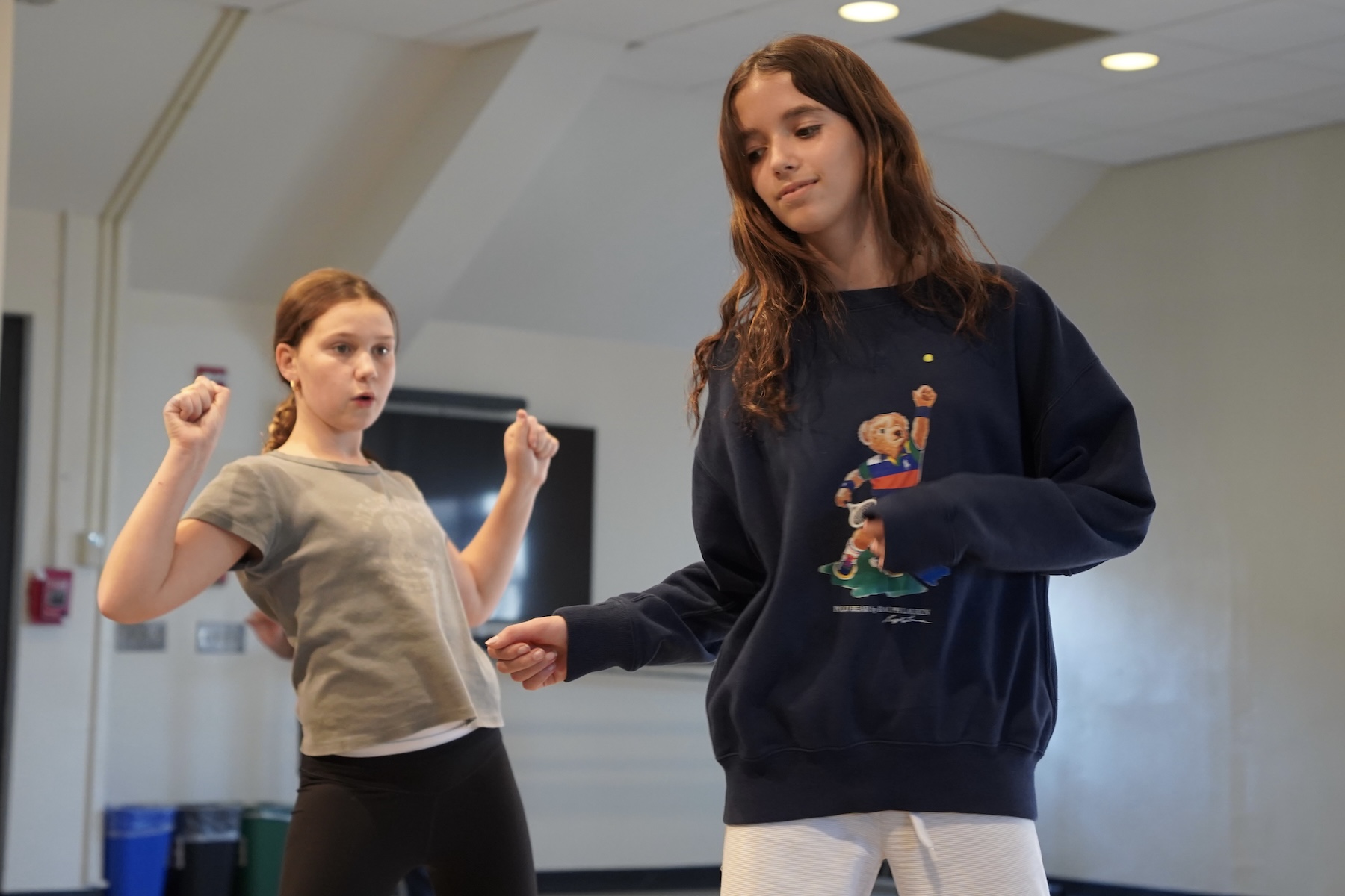 Two Fieldston Middle students dance with looks of concentration on their faces in a dance class