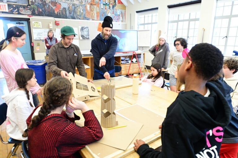 Students gathered around a cardboard model during a classroom workshop