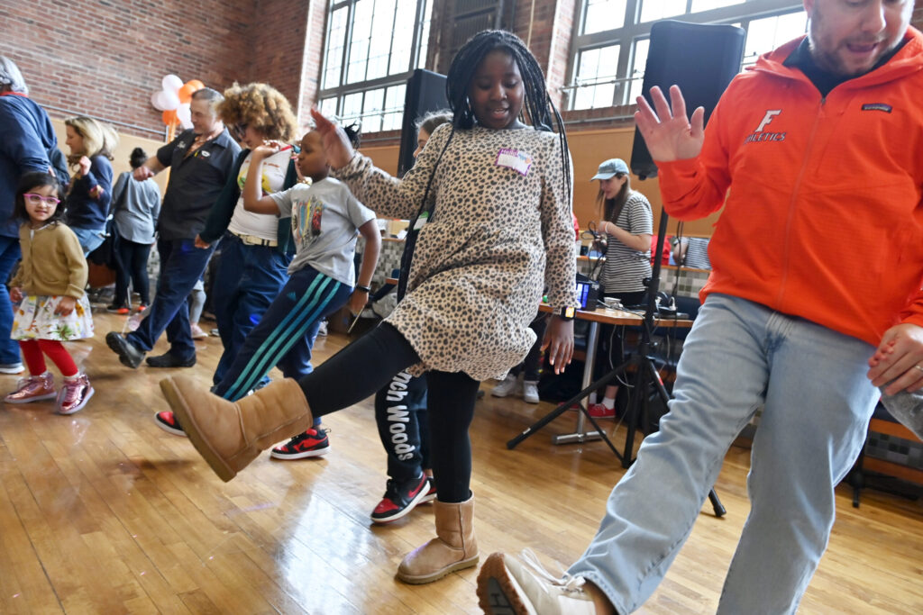 A group of students and teachers dance in the dining hall