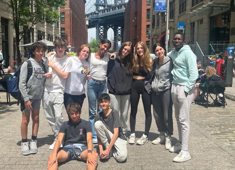 Group of 8th Graders pose together in Dumbo, Brooklyn, in front of a bridge