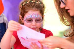 Student with face painted looks at piece of paper