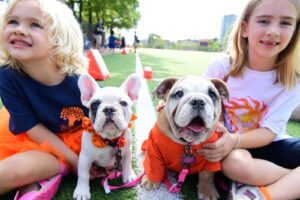 Young students pose and smile with puppies