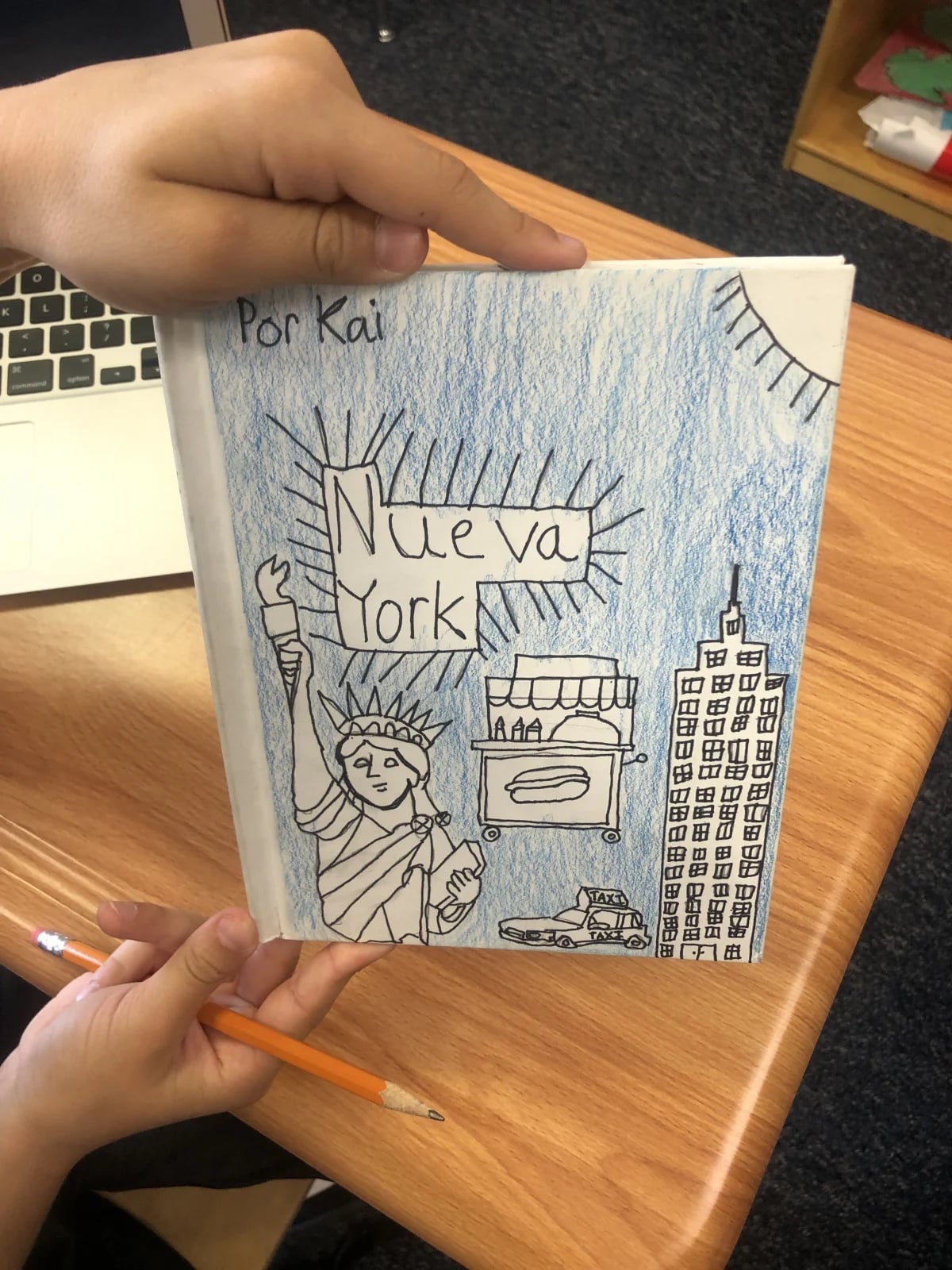 An Ethical Culture Fieldston School 5th Grader holding the book they made as part of the Spanish book project