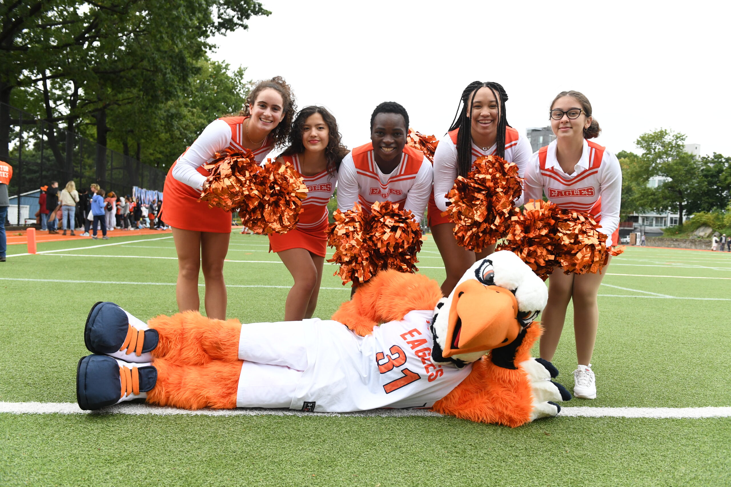 Eagle Cheer poses with shiny orange pompoms with the Eagle