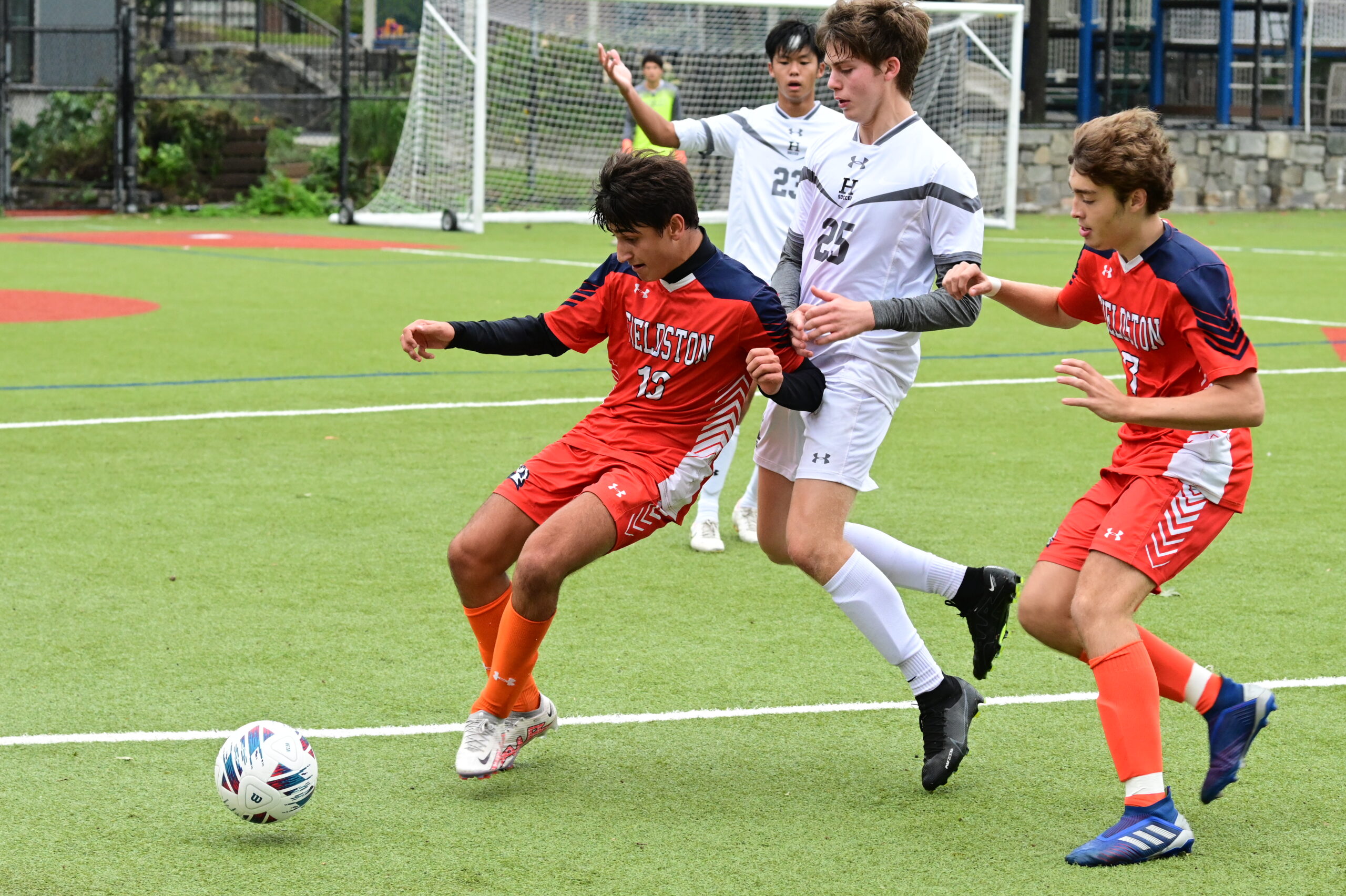 Players on the boys soccer team run after the ball during a game