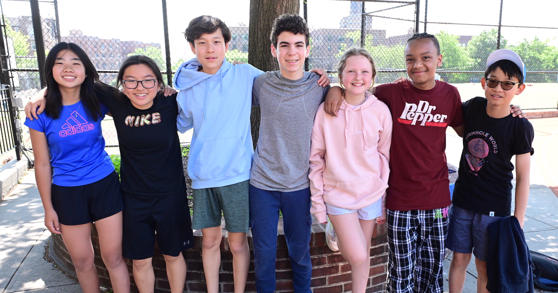 Ethical Culture Fieldston School Middle School Students stand together arms around each other smiling in the field