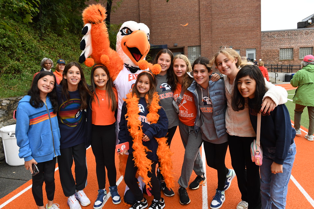 Group of ECFS students gather on Upper Field during Homecoming posing with the Fieldston Eagle mascot.