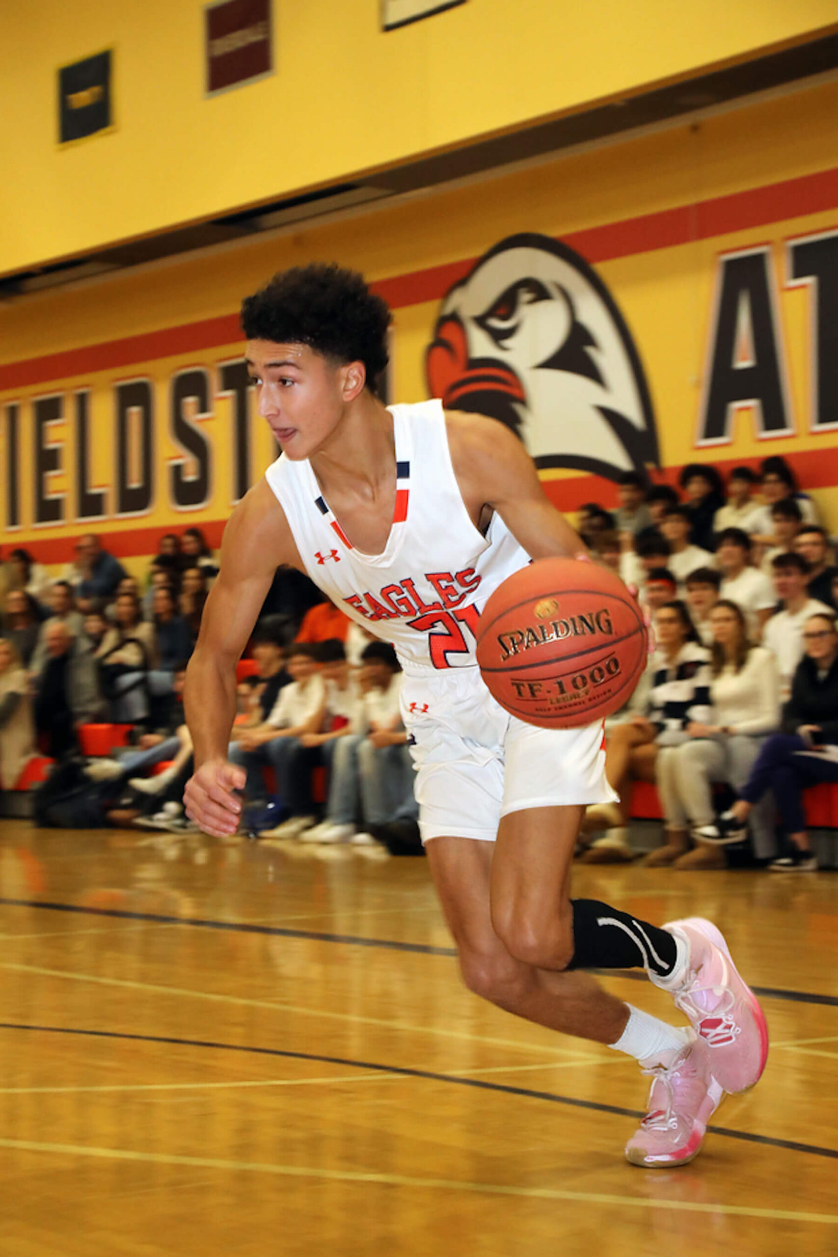 Fieldston Upper boys basketball player dribbles down the court in white Fieldston uniform.