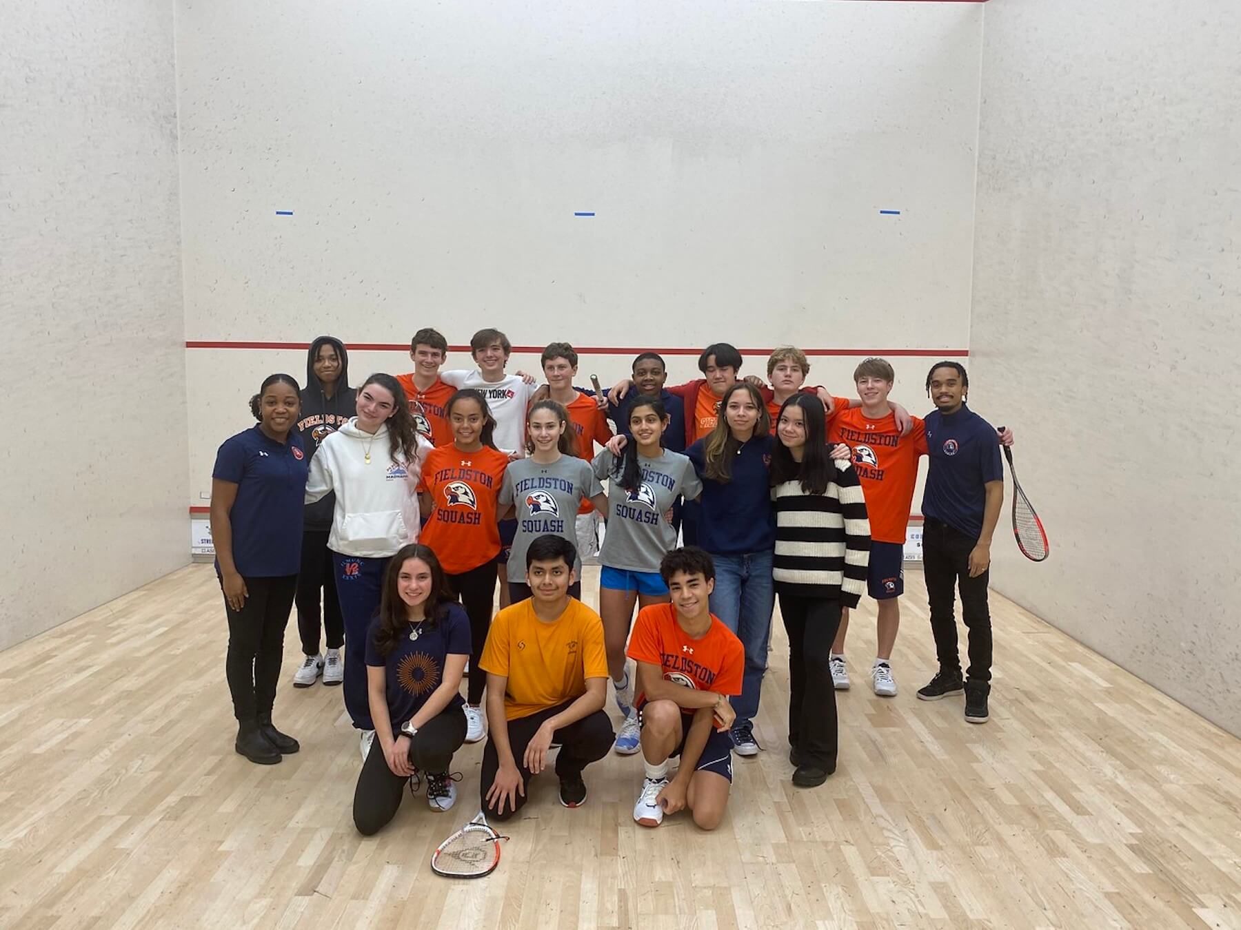 Fieldston Upper squash team poses for group photo inside squash court.