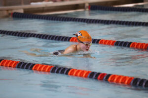 Fieldston Upper swim team member competes in breast stroke race in the pool.
