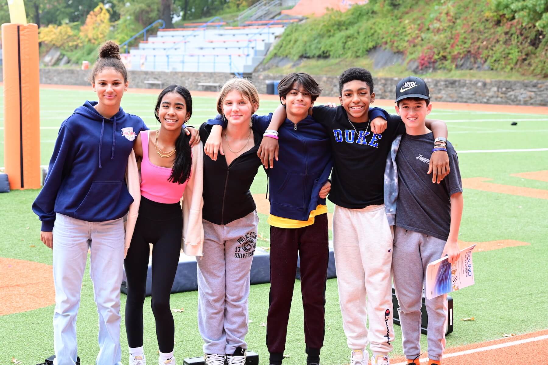 Ethical Culture Fieldston School Middle School students stand together in arms on athletic field