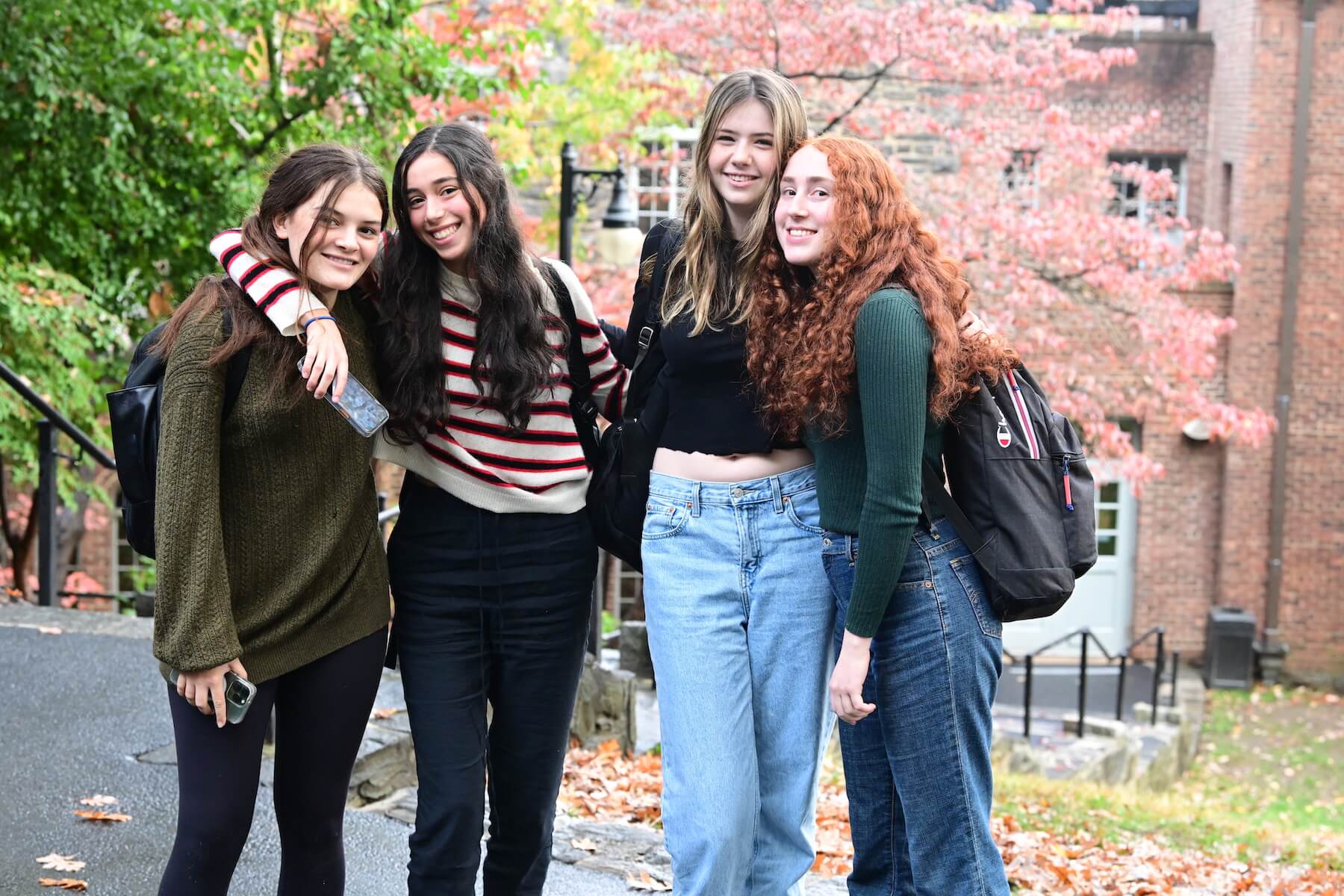 Ethical Culture Fieldston School Upper School students stand together in arms on campus quad