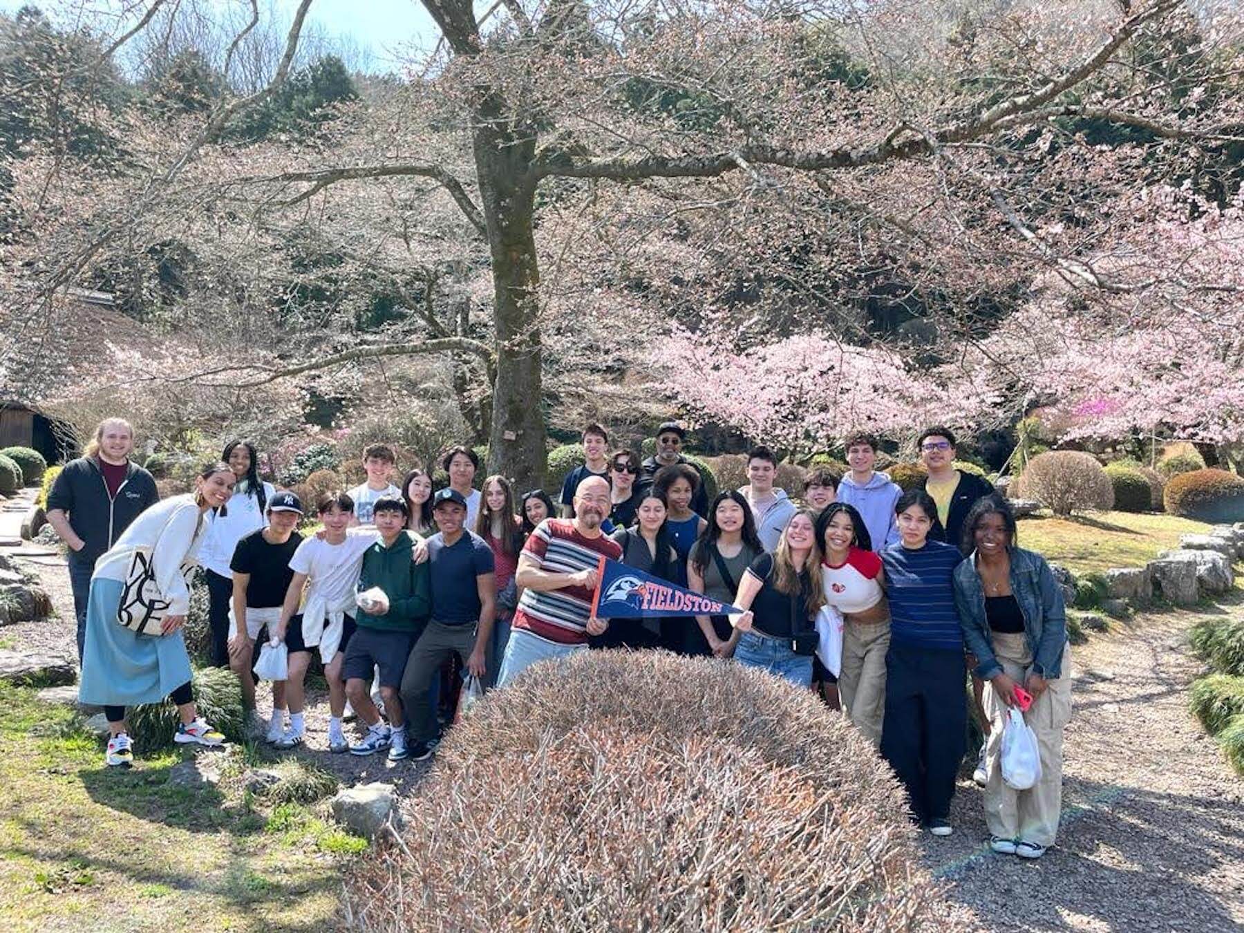 Group of Ethical Culture Fieldston School Upper School students standing under cherry blossoms during trip abroad to Japan