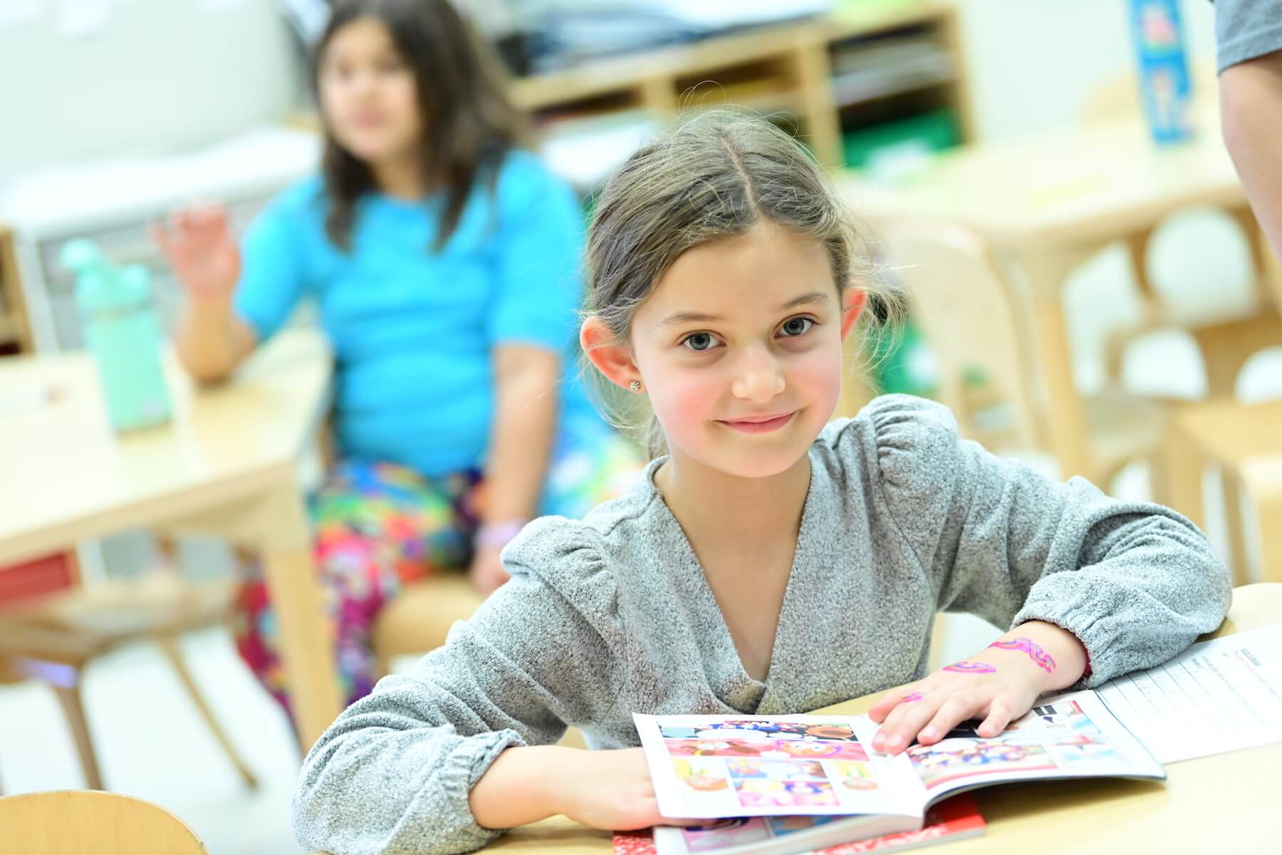 Ethical Culture Fieldston School student reading at desk pauses to smile for the camera