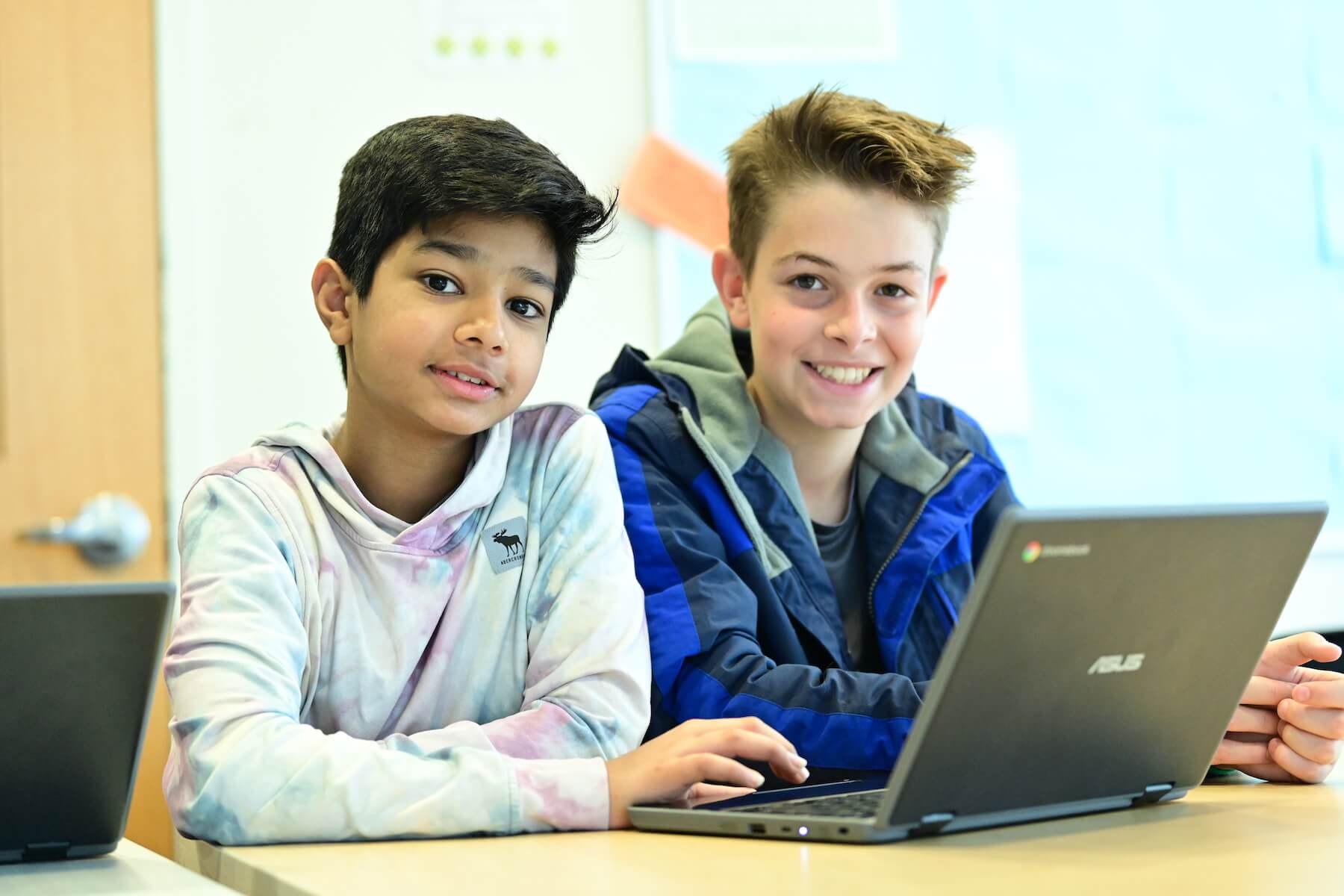 Ethical Culture Fieldston School Middle School students working together on computer pause to smile for the camera