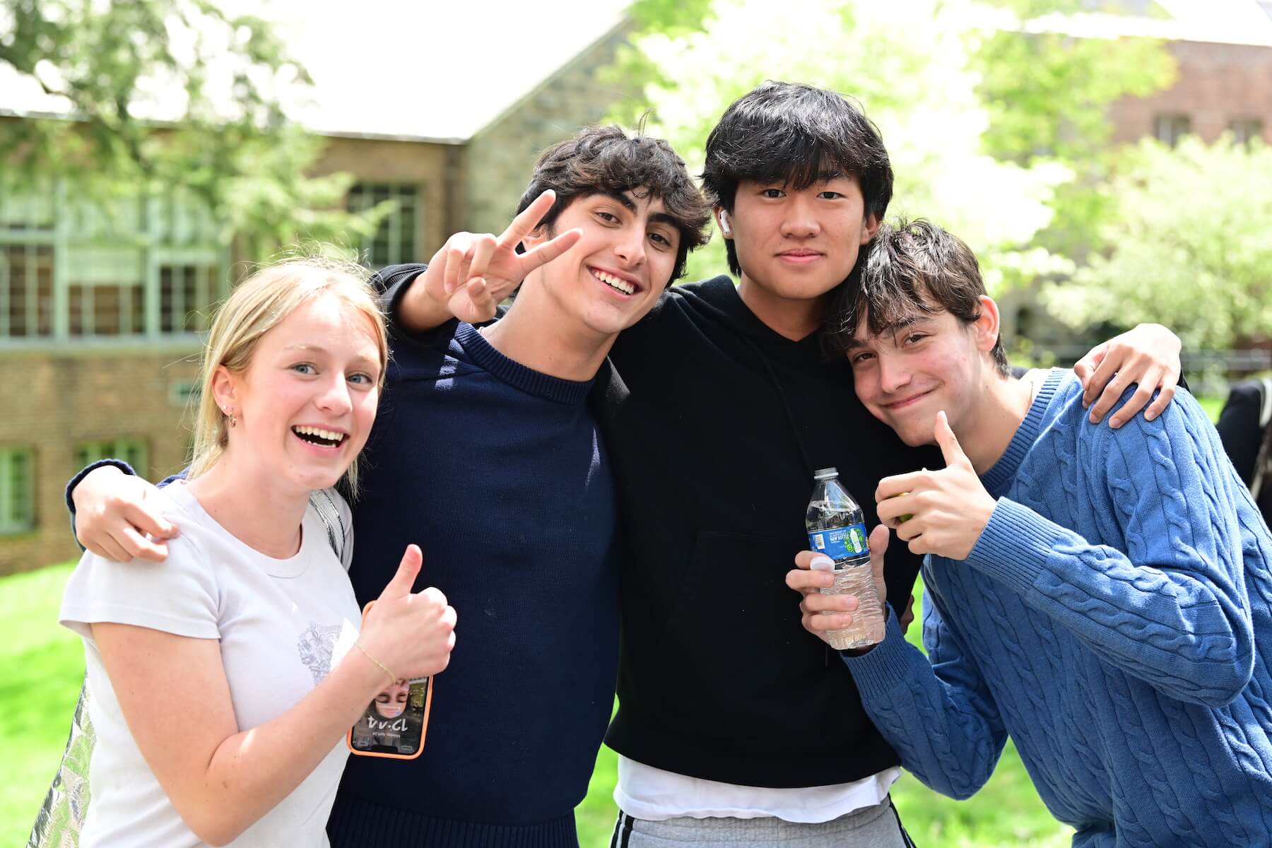 Ethical Culture Fieldston School Fieldston Upper students sit smile at camera in the quad during the College Symposium