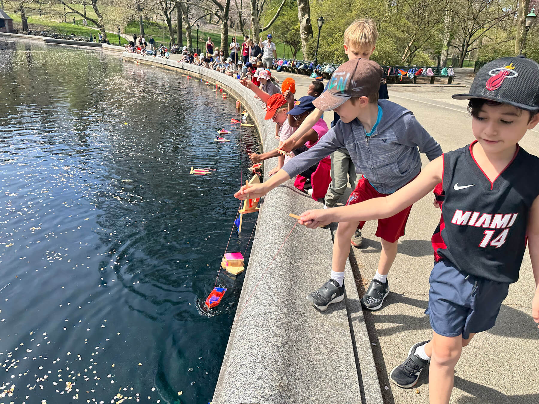 Group of Ethical Culture Fieldston School Ethical Culture students launching handmade sail boats into water in Central Park