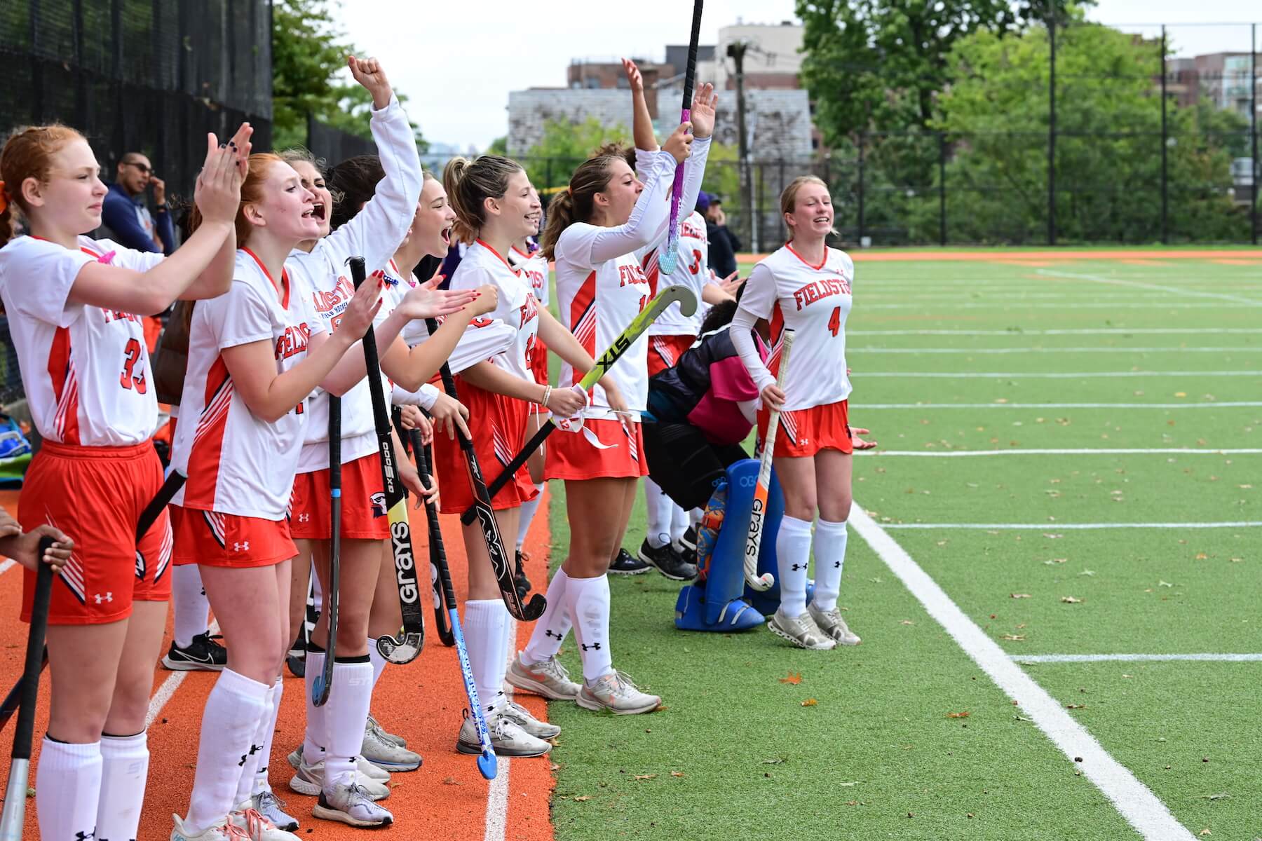 Fieldston Upper field hockey team celebrates on sideline at Homecoming 2022.