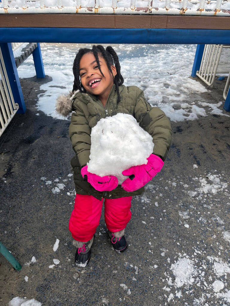 Ethical Culture Fieldston School Fieldston Lower Student proudly carries a giant snowball on the playground