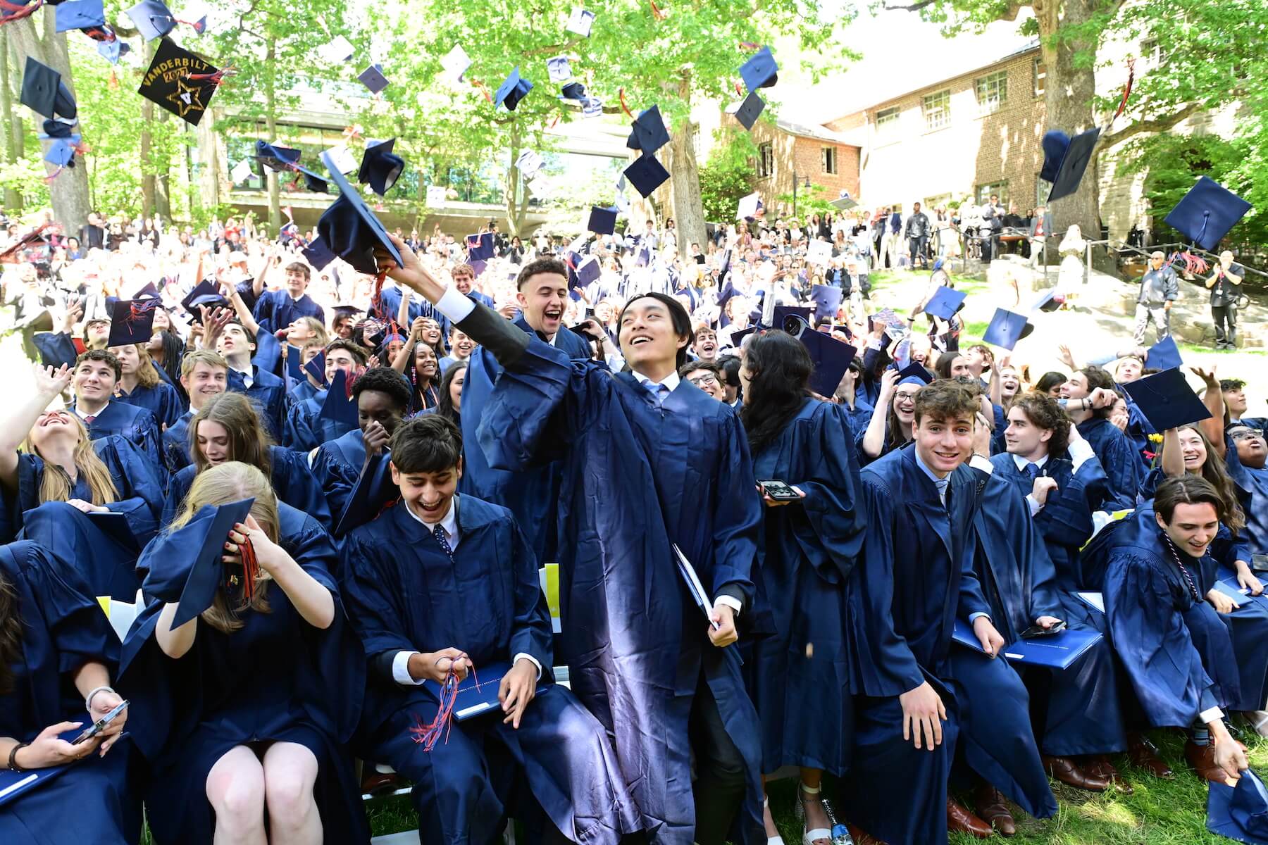 Ethical Culture Fieldston School Upper School graduates celebrate by tossing their caps into the air