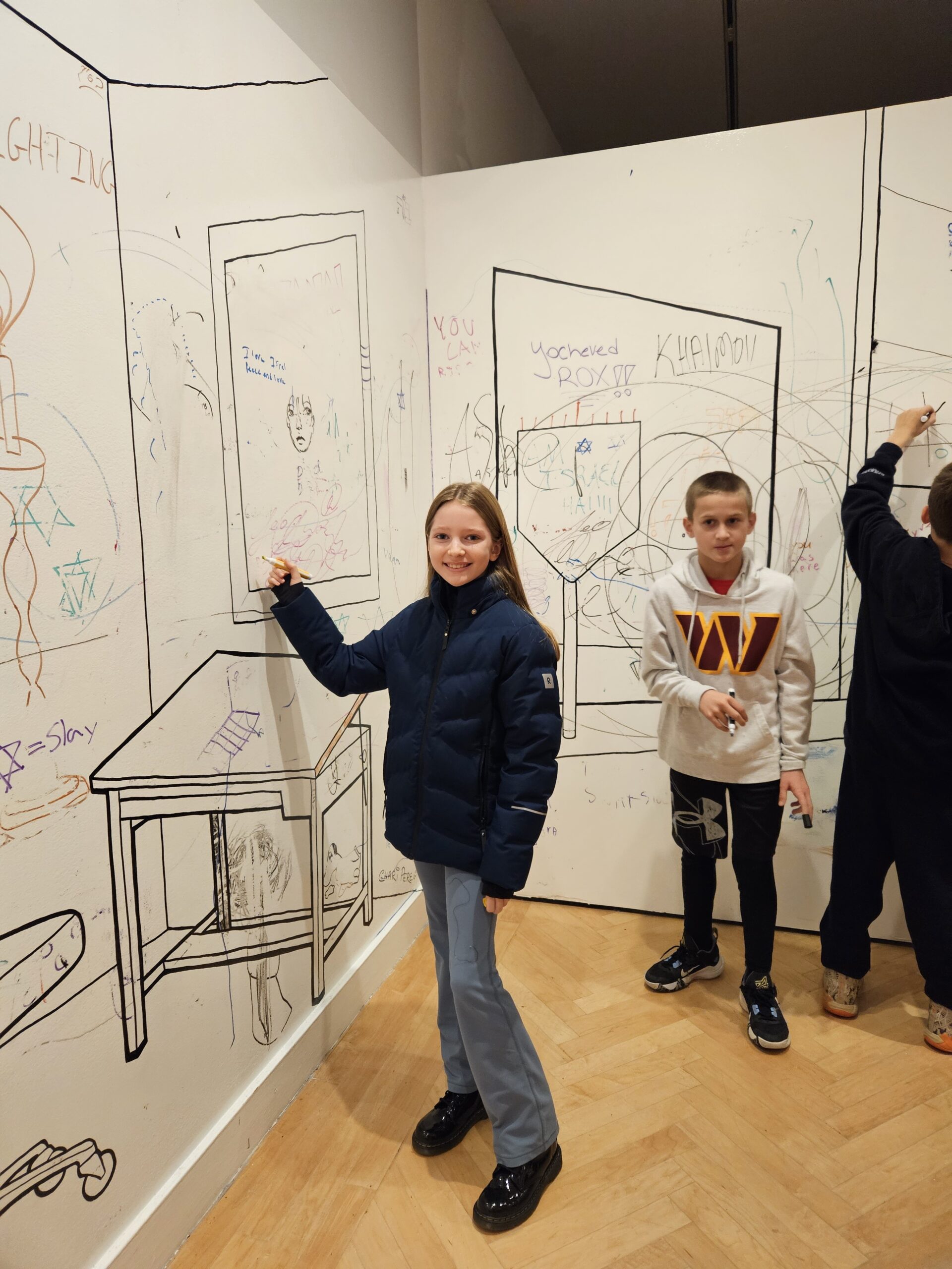 ECFS student poses in front of large whiteboard at Jewish experience museum.