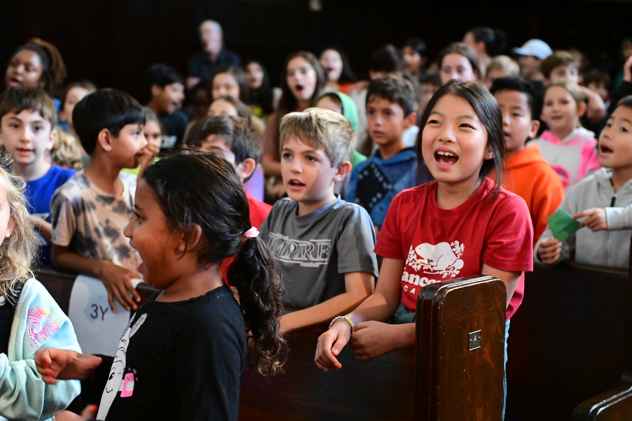 Ethical Culture students sit and sing the school song at the opening assembly honoring Lucy Simon Levine ’58.