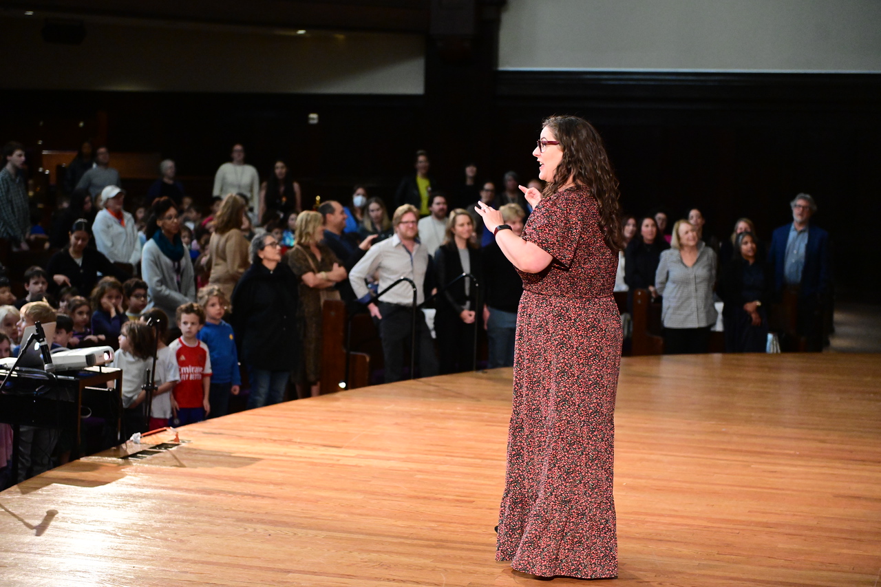 Ethical Culture music teach Amy Travis leads the audience in song.