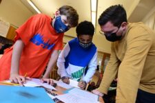 Ethical Culture Fieldston School Ethical Culture students standing over work with teacher engaged in discussion