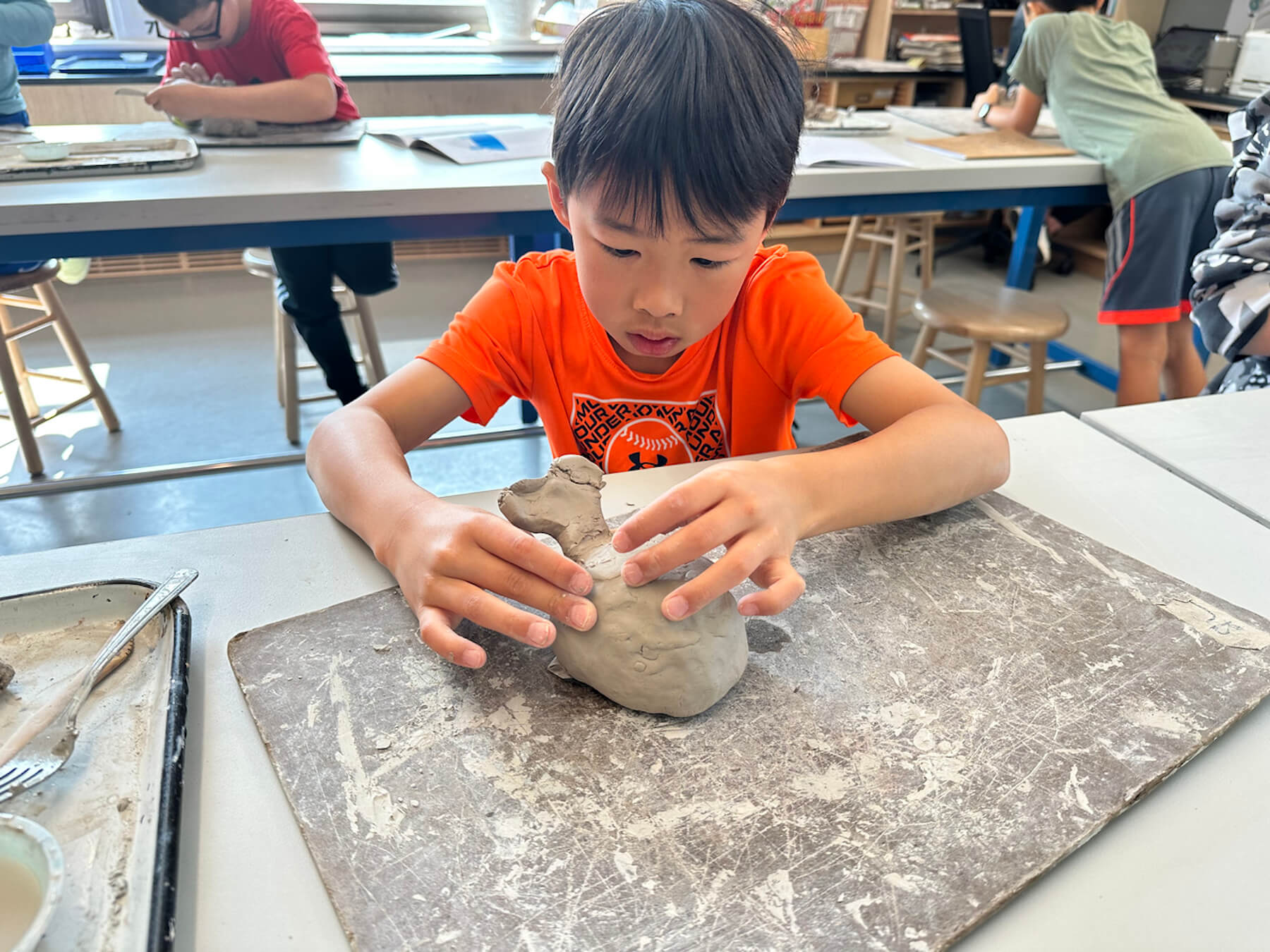 Ethical Culture student diligently works on his ceramics animal mug in the art classroom.