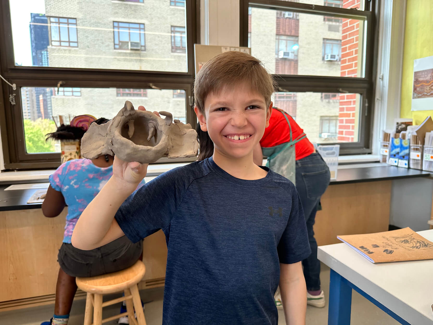 Ethical Culture student smiles and poses with his ceramics project in progress.