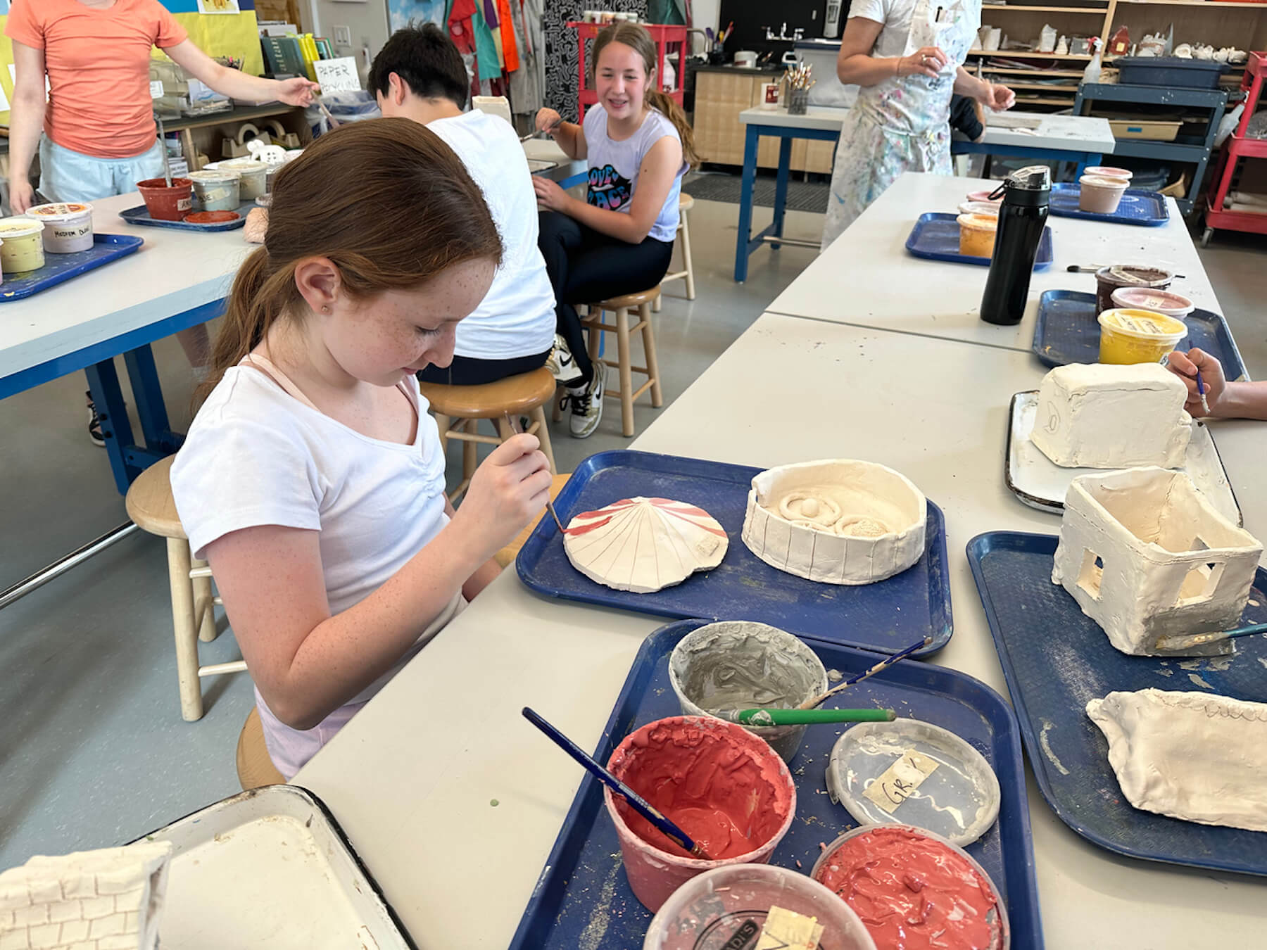 Ethical Culture 5th Grader paints her circus themed ceramics project.