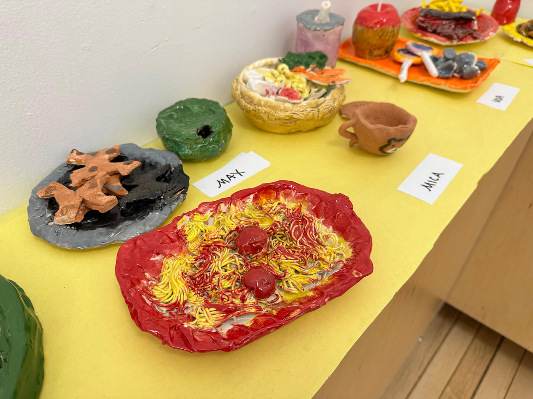 Ethical Culture 4th Grade ceramics projects (food sculptures) sit on display in hallway outside of art classroom.