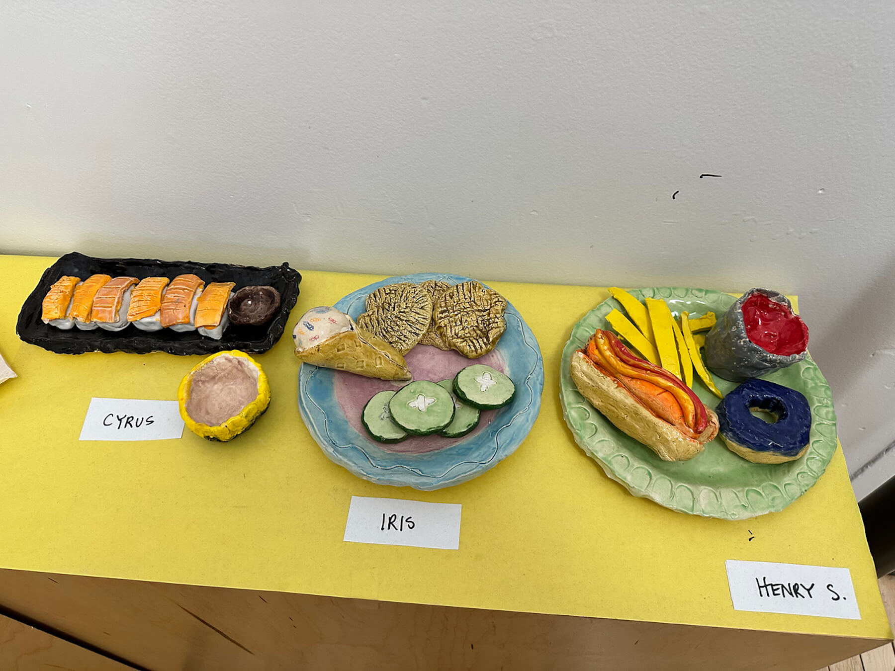 Ethical Culture 4th Grade ceramics projects (food sculptures) sit on display in hallway outside of art classroom.