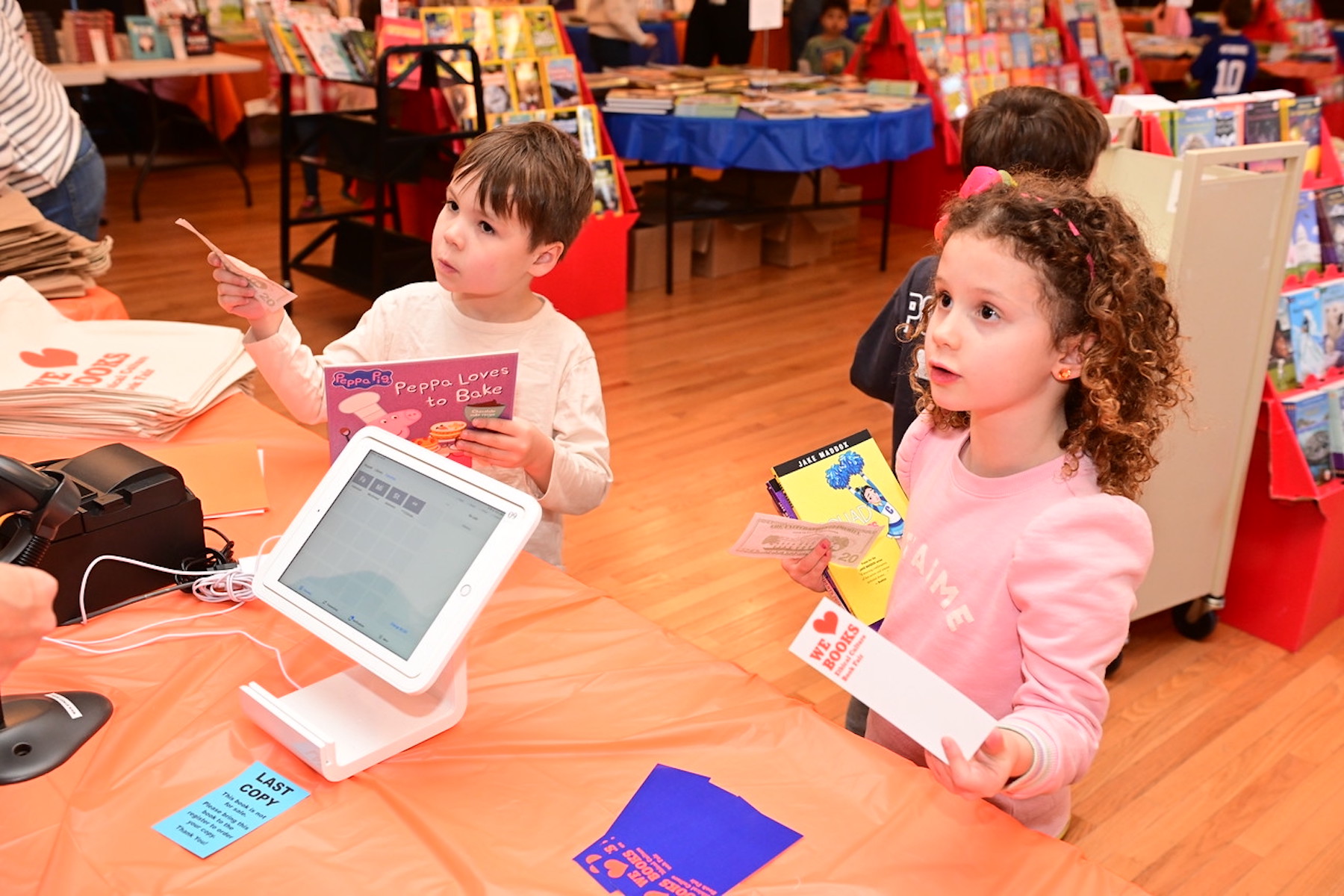 Two young Ethical Culture students pay for their books using fake money provided by the School.