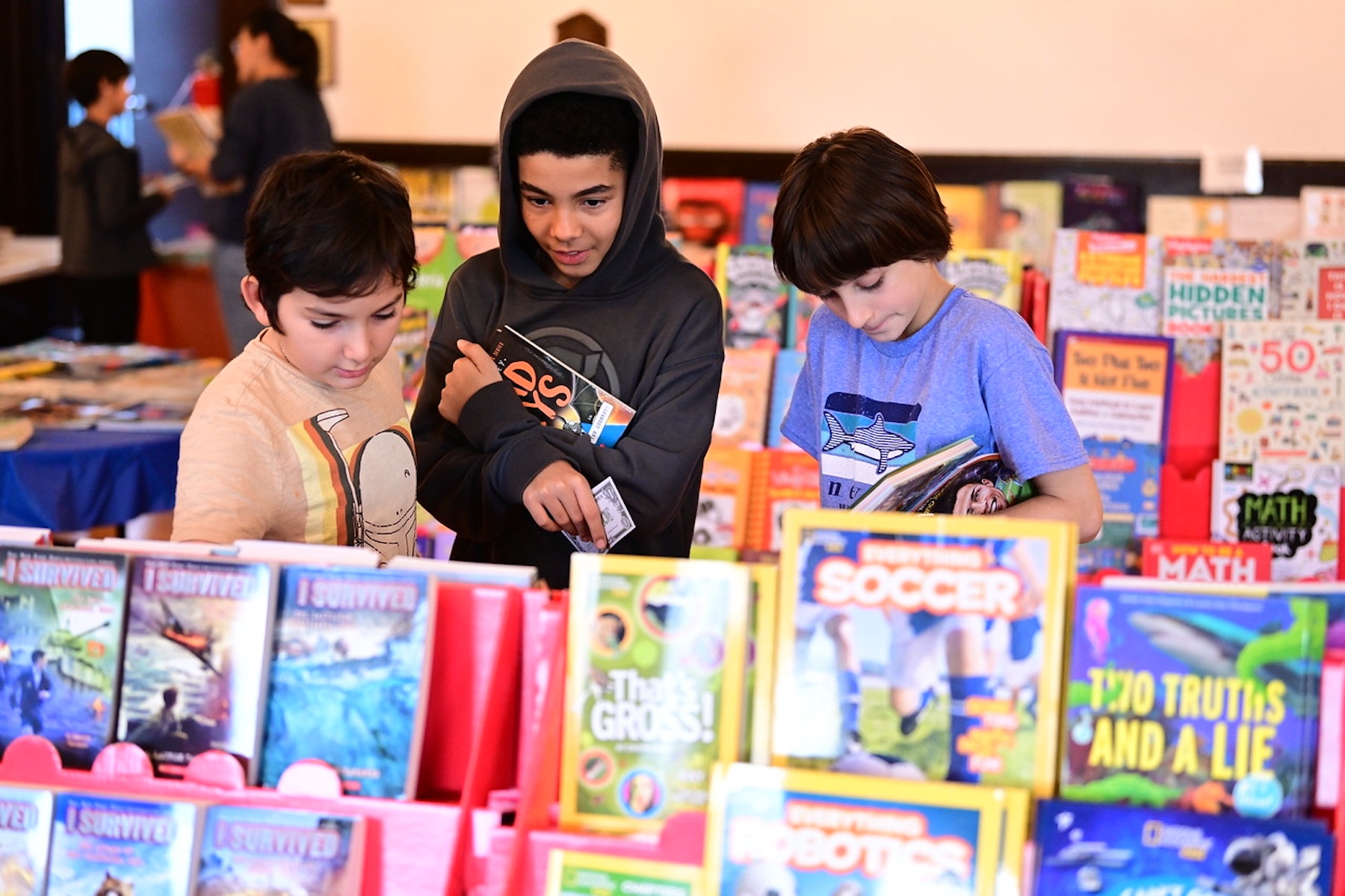 Three Ethical Culture students shop for books at the annual Book Fair.
