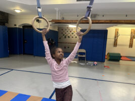 Ethical Culture student swings on rings at after school gymnastics class.
