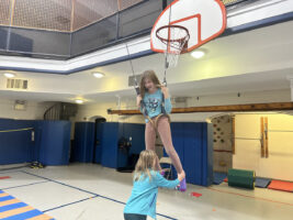 Student swings on gymnastics rings at Ethical School after school class.
