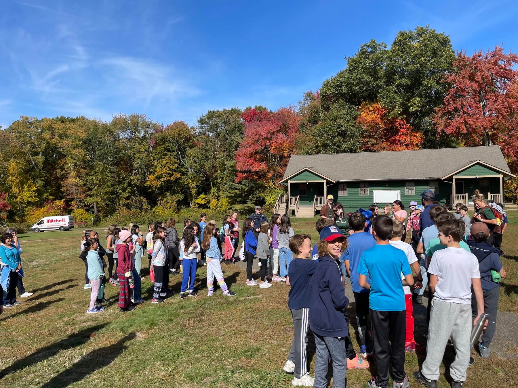 Ethical Culture students stand outside in nature, gathered in groups.