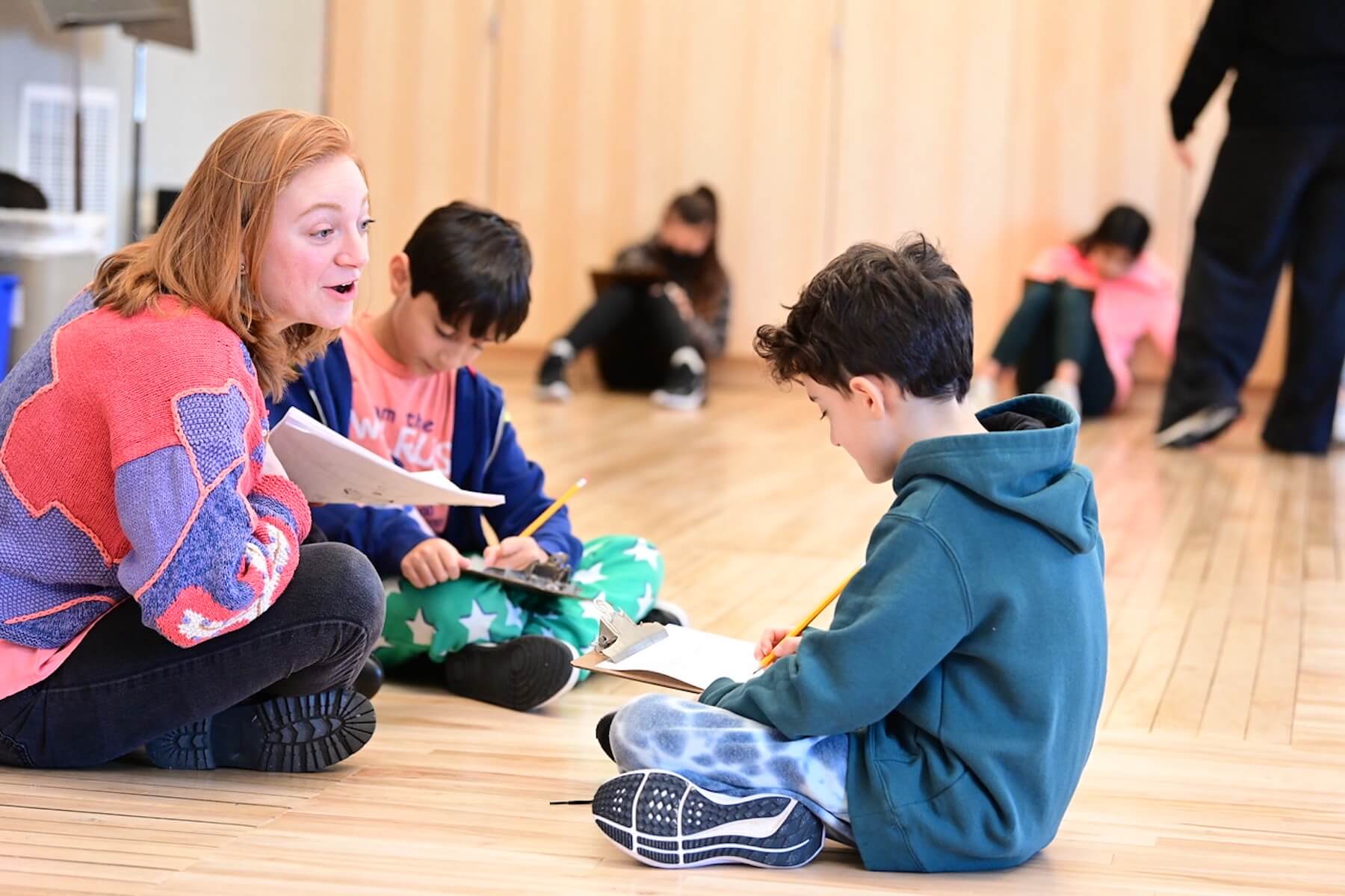 Crystal-Marie Alberson assists students while they write a potential scene for the 4th Grade play.