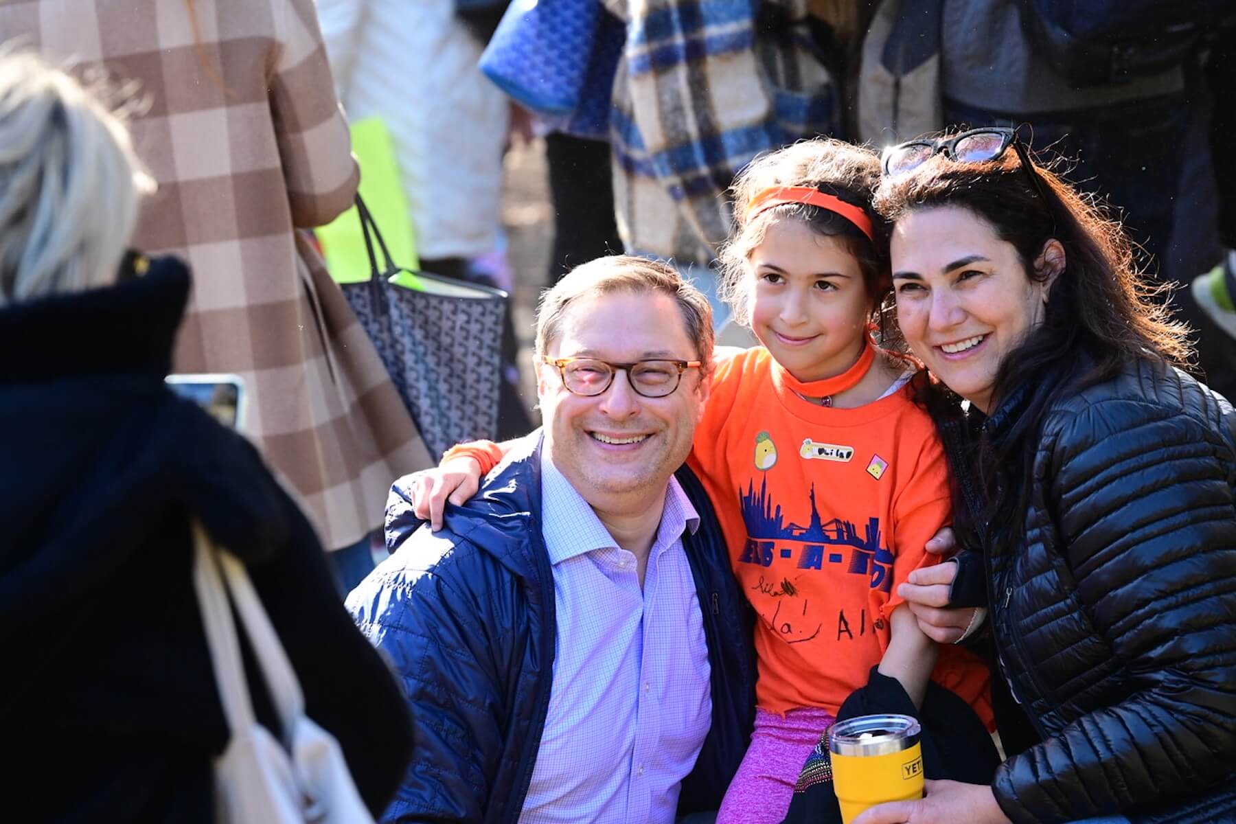 Ethical Culture student smiles with parents/guardians outside at ECS-a-Thon.