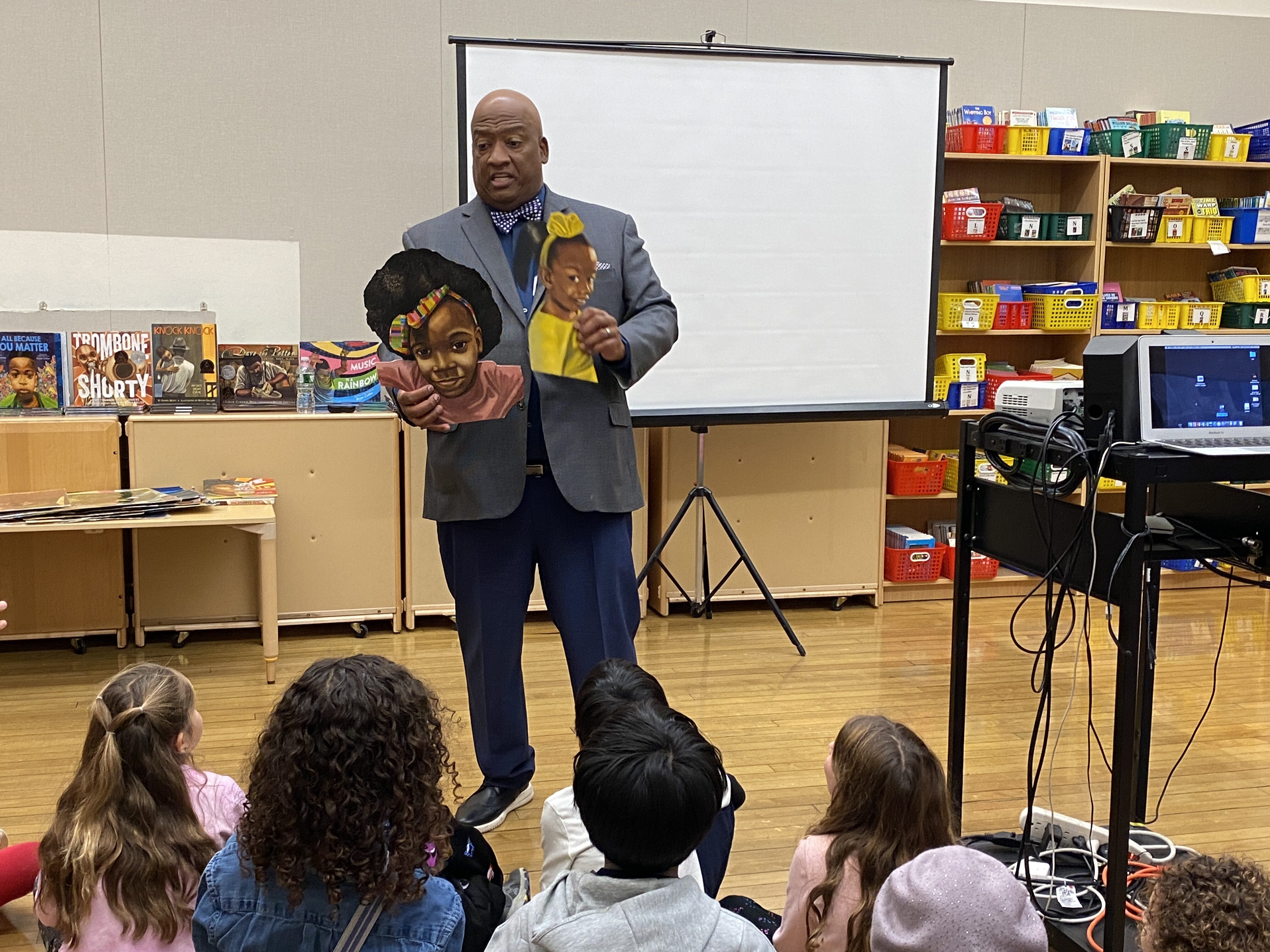 Bryan Collier holding two illustrations of girls from his picture book