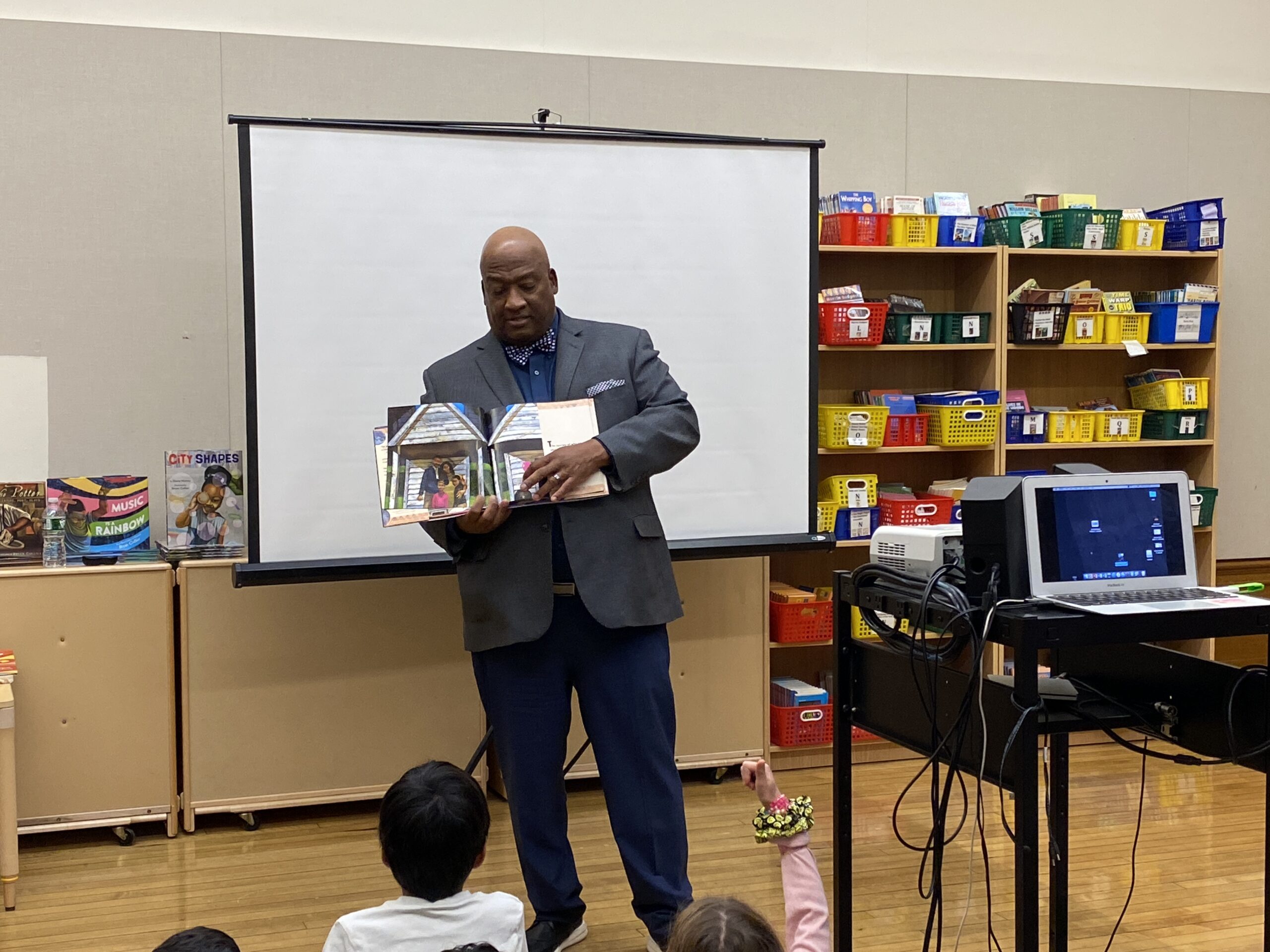 Bryan Collier reading out loud from a picture book to students
