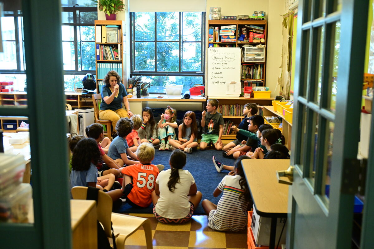 A group of students sit in a circle looking at their teacher at Fieldston Lower