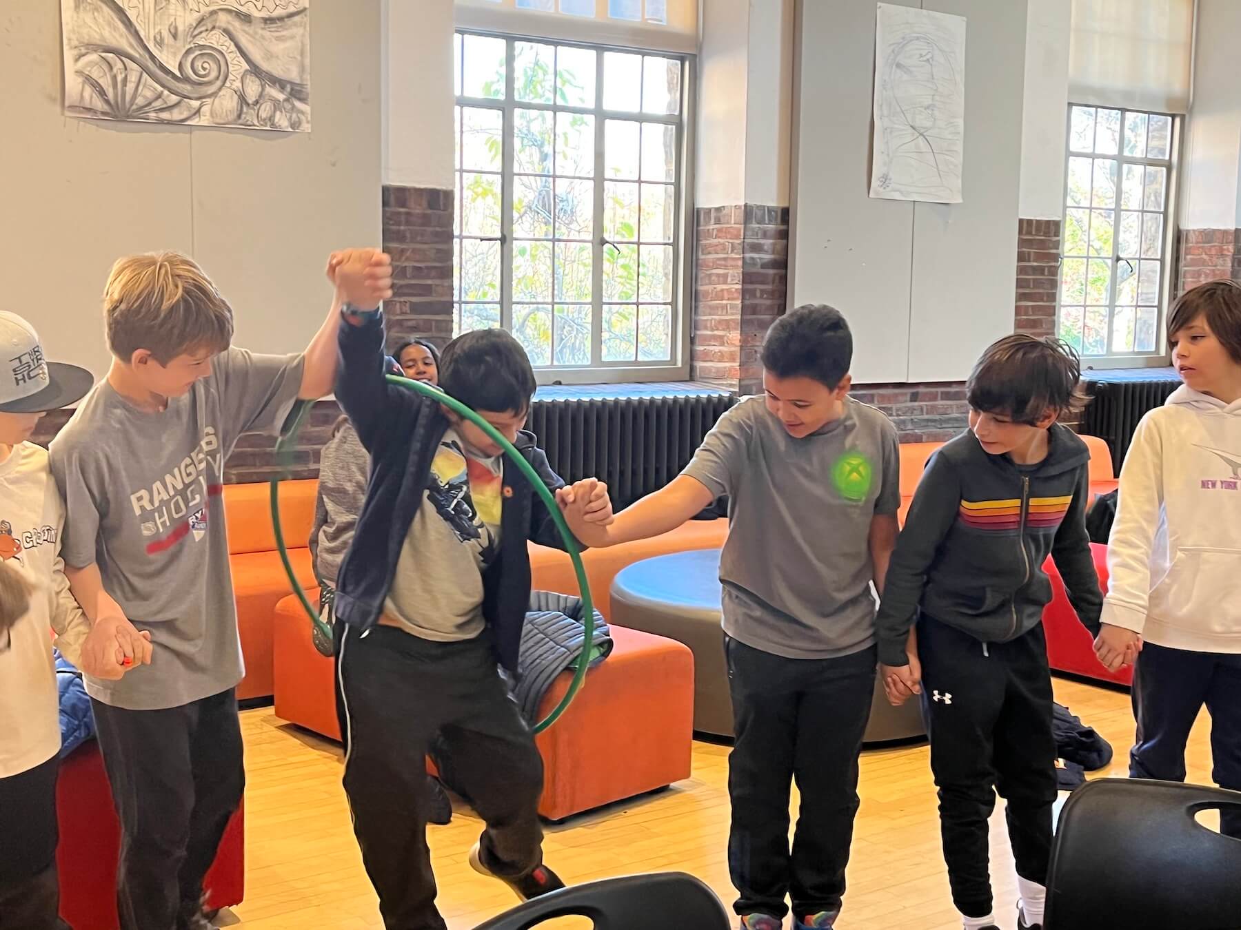 Ethical Culture Fieldston School Fieldston Lower students participating in team building activity by passing a hola hoop around a circle