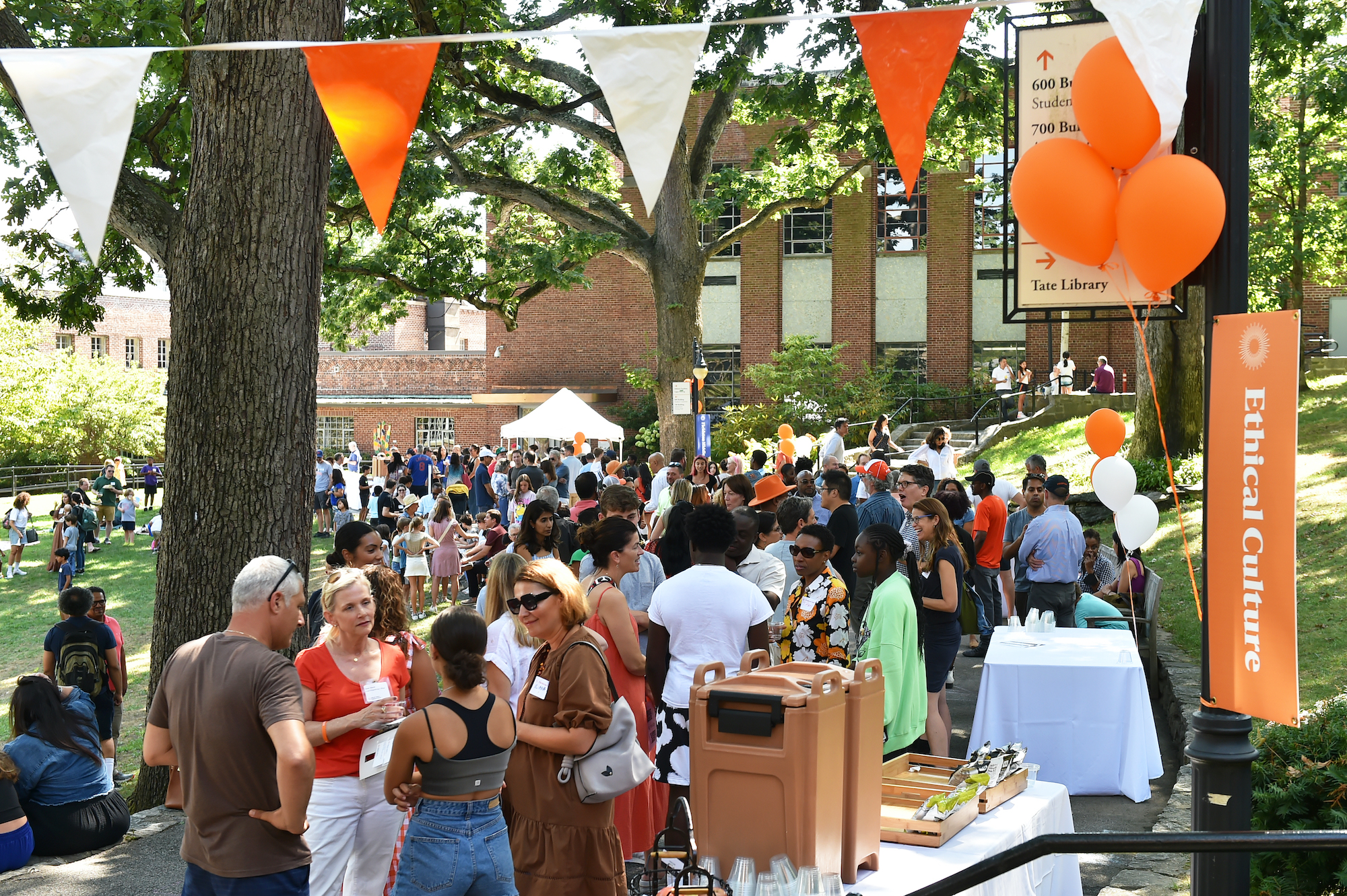 A large crowd gathers under orange balloons on the Quad at the back to school celebration