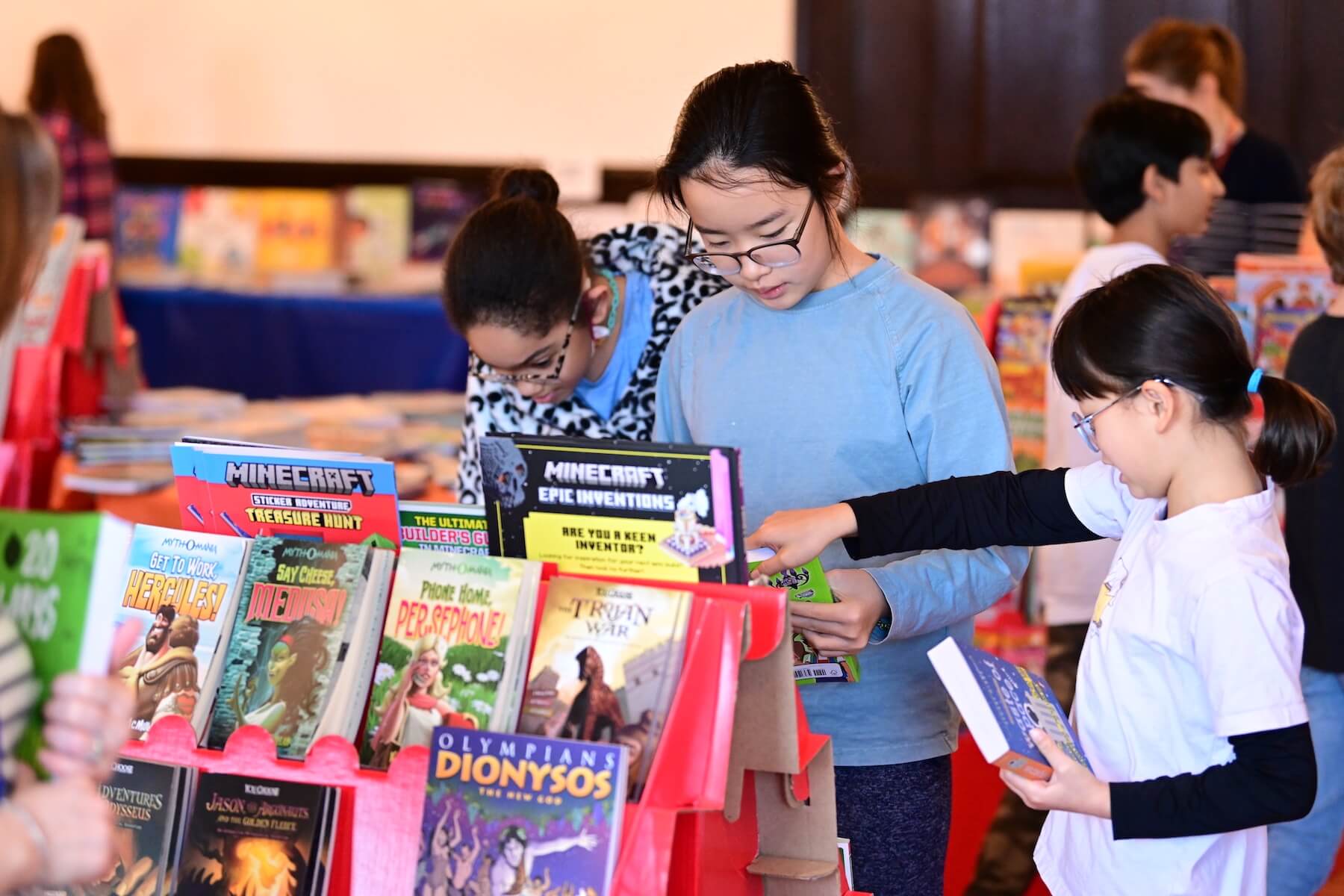 Three Ethical Culture Fieldston School students look at books during Ethical Culture's Book Fair