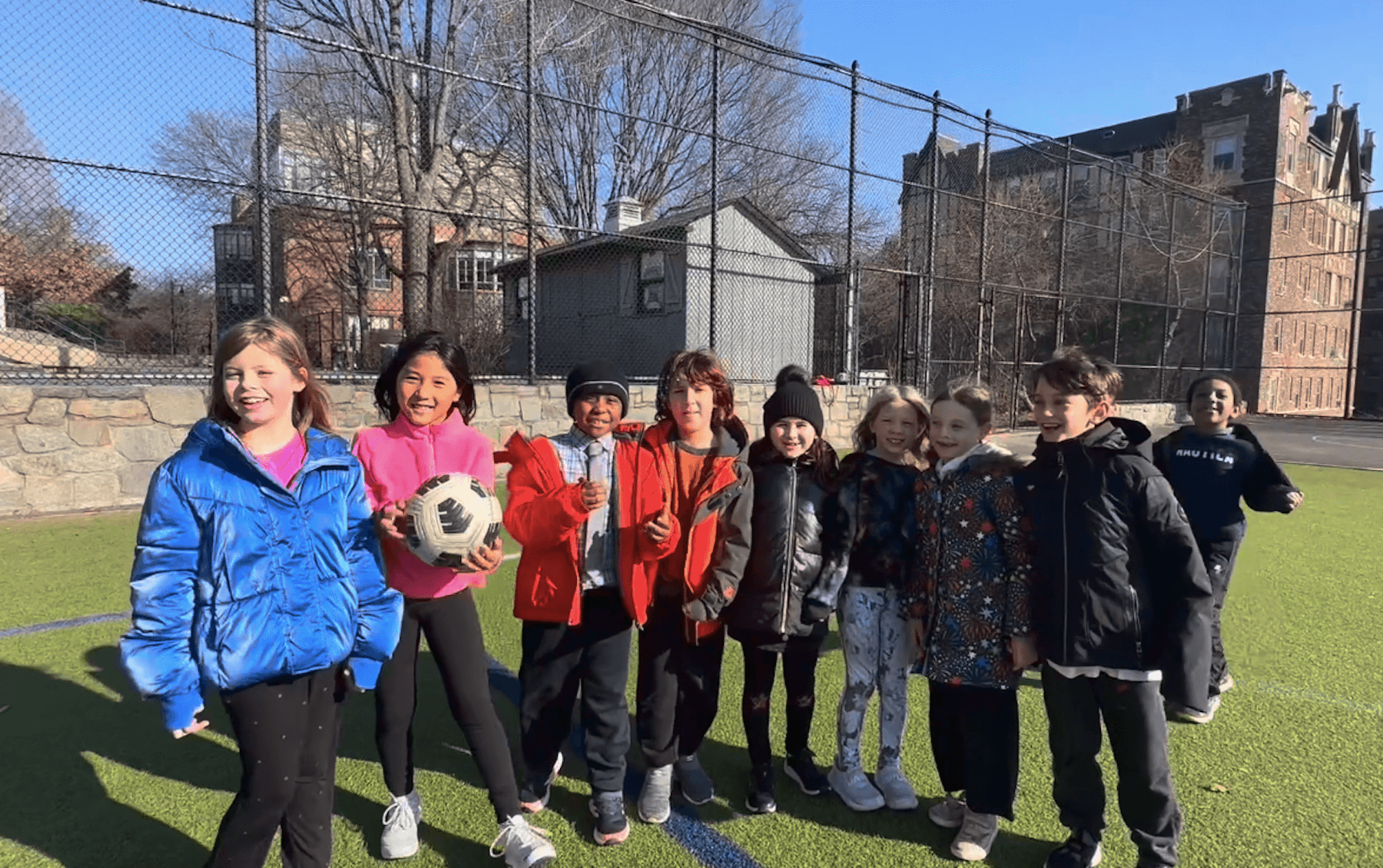 A group of 2nd Grade Ethical Culture Fieldston School students from Fieldston Lower stand smiling together smiling