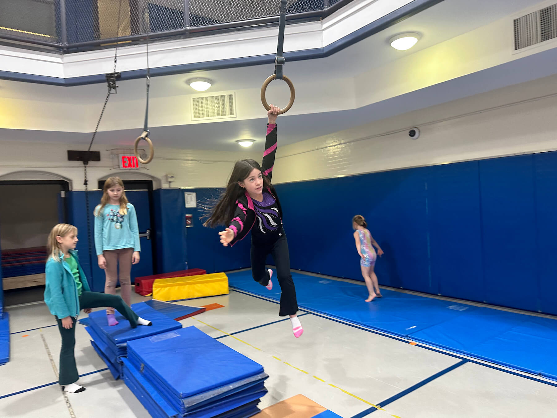 Ethical Culture Fieldston School student swings from rings in after school gymnastics class