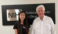 Vivian Lee and Jonathan Pollock pose in front of a large sign for the National Institute on Drug Abuse